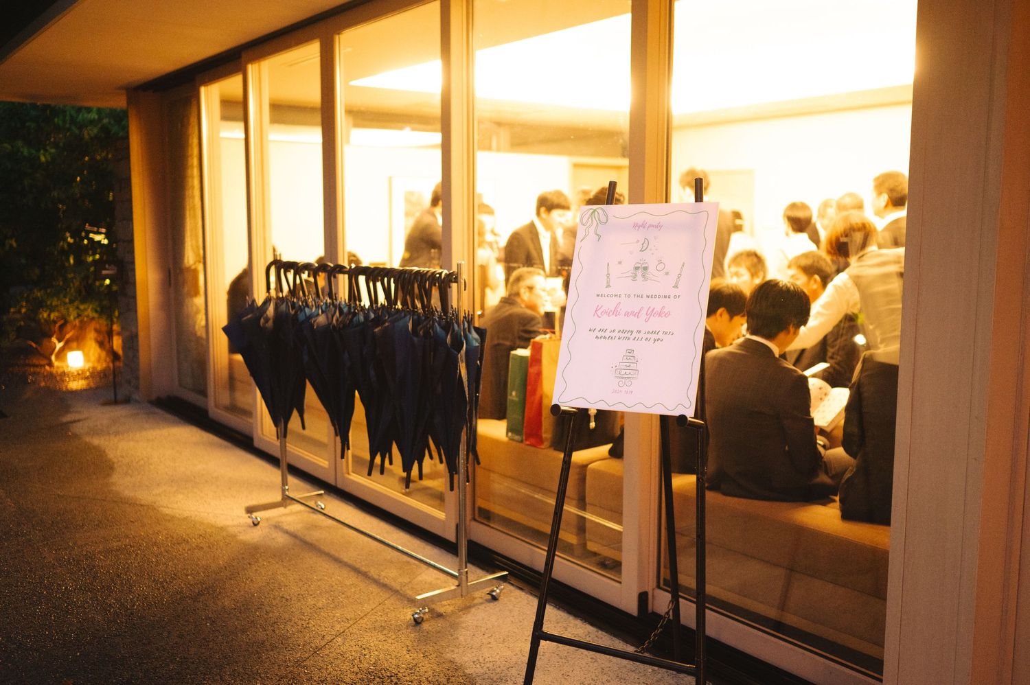 Interior view of a brightly lit venue space with guests visible through large windows.