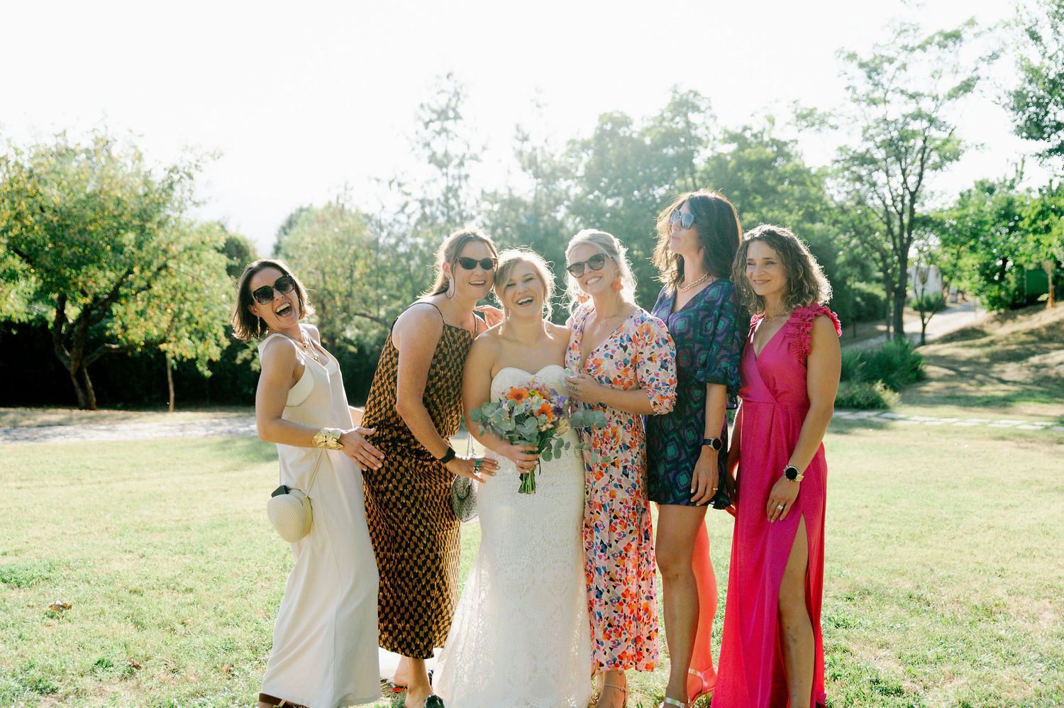 Wedding party and guests pose together during an outdoor summer celebration.