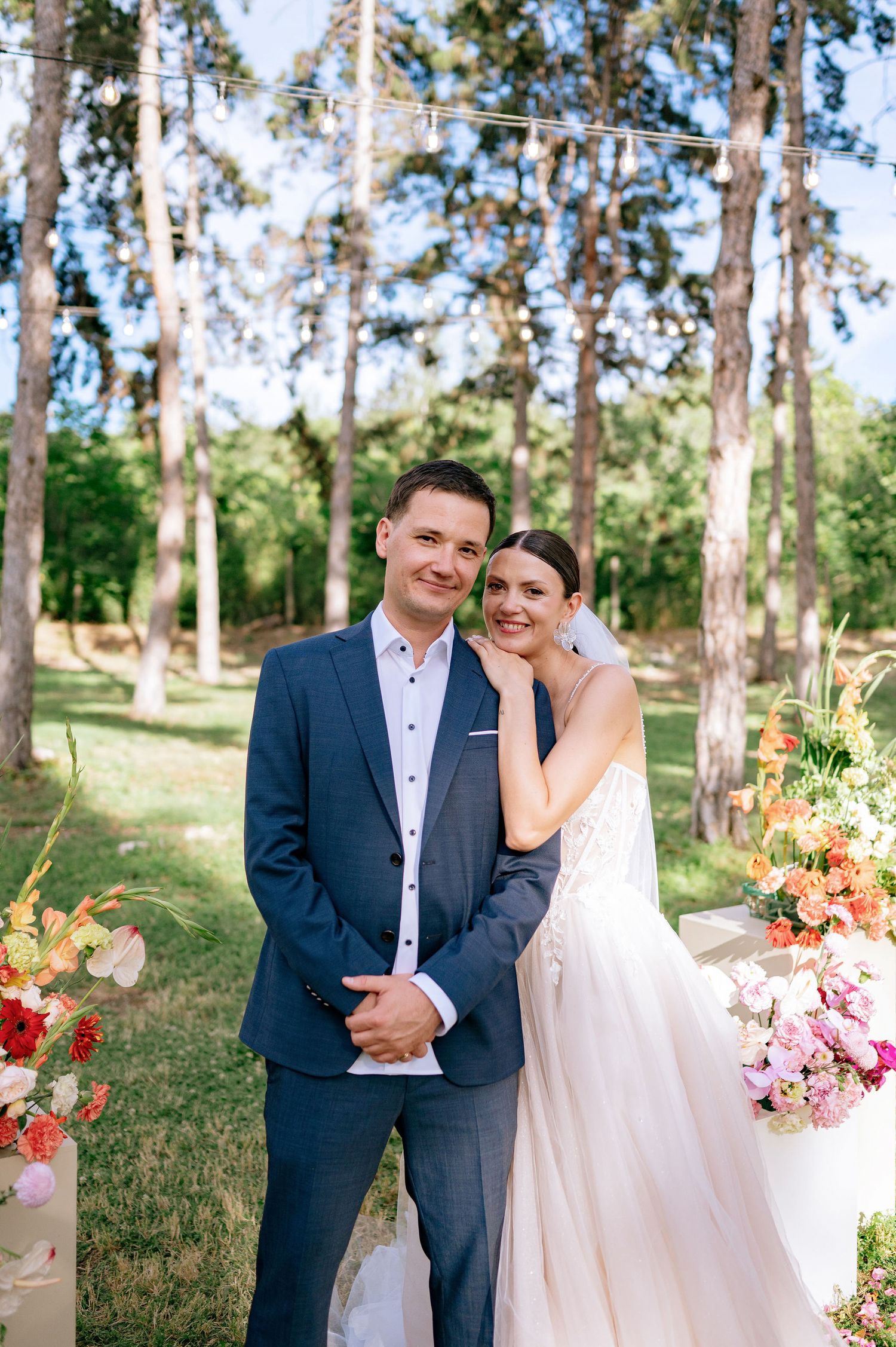 A joyful wedding moment captured in a natural forest setting with decorative floral arrangements.