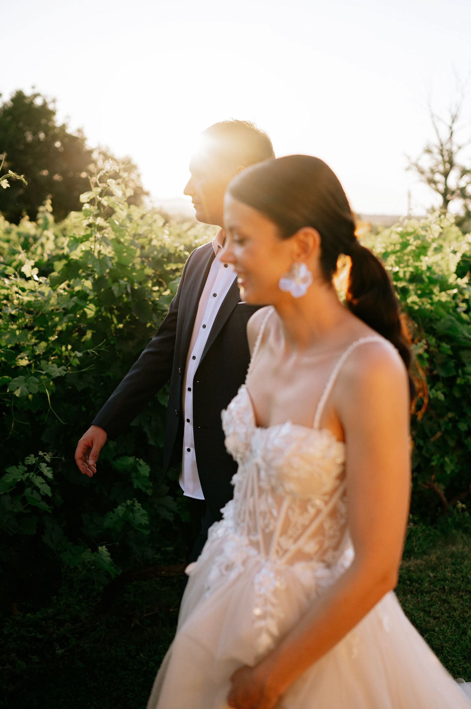 Joyful wedding scene with sunlit garden and cypress trees in background.