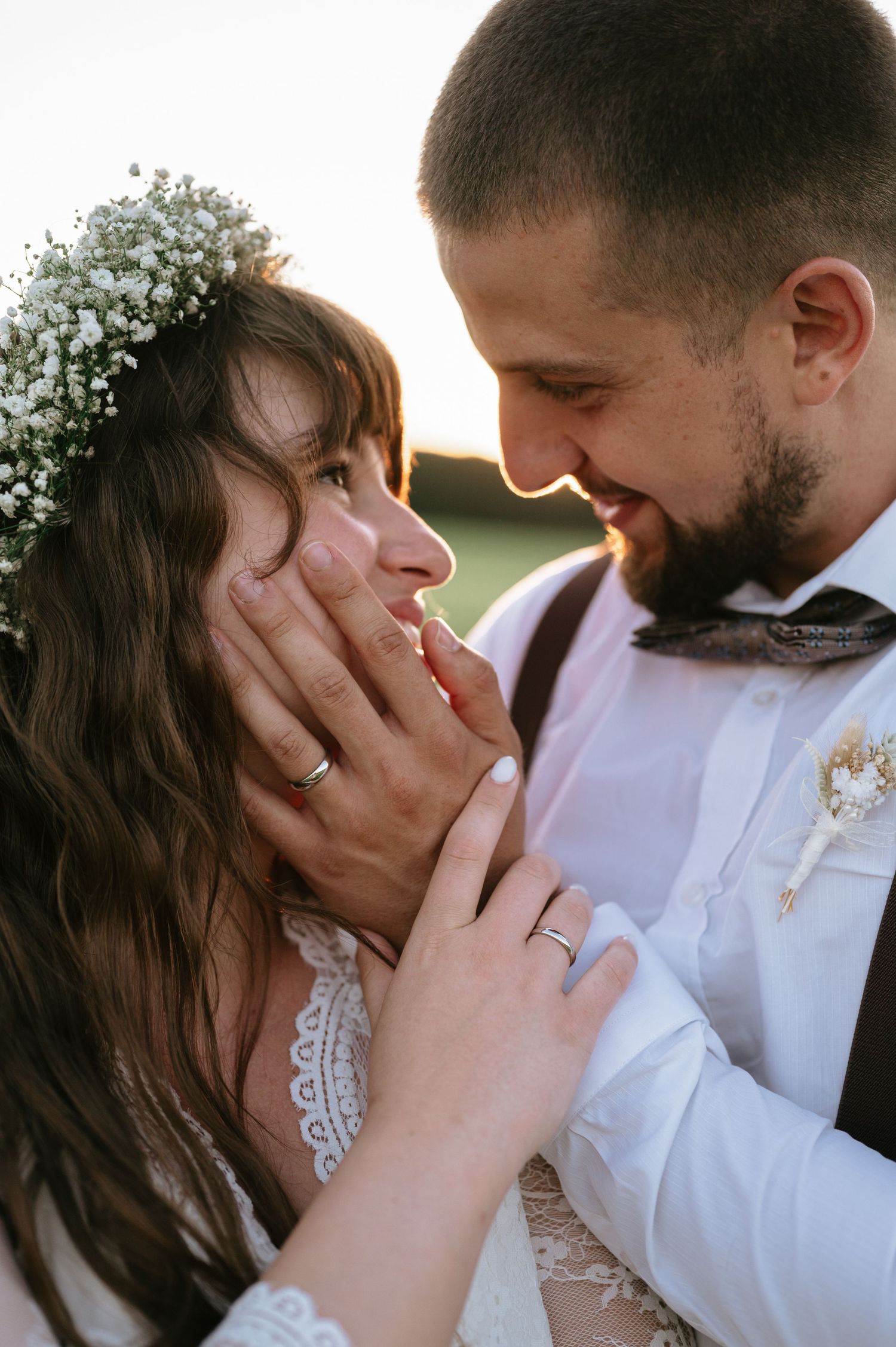 Romantic close-up of wedding couple with baby's breath floral crown at sunset.