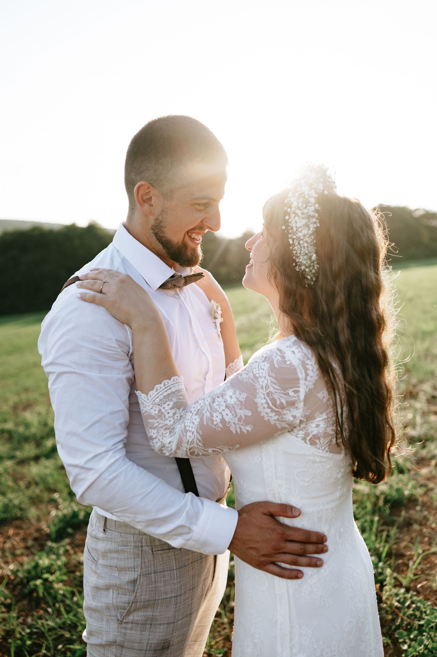 Sunlit wedding portrait capturing tender moments in a rustic outdoor setting.