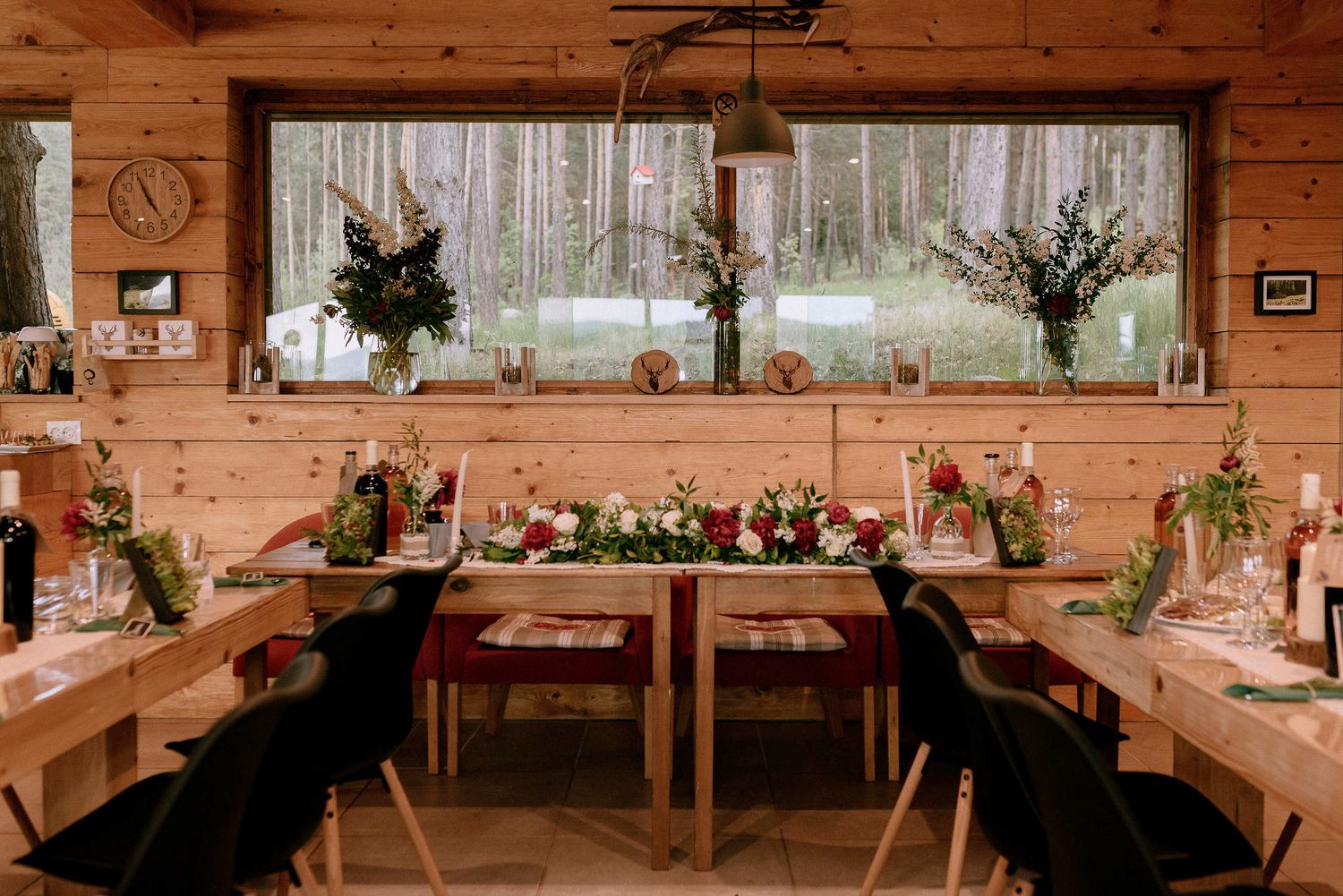 Wide view of a rustic barn wedding venue with wooden beams and elegant table arrangements.