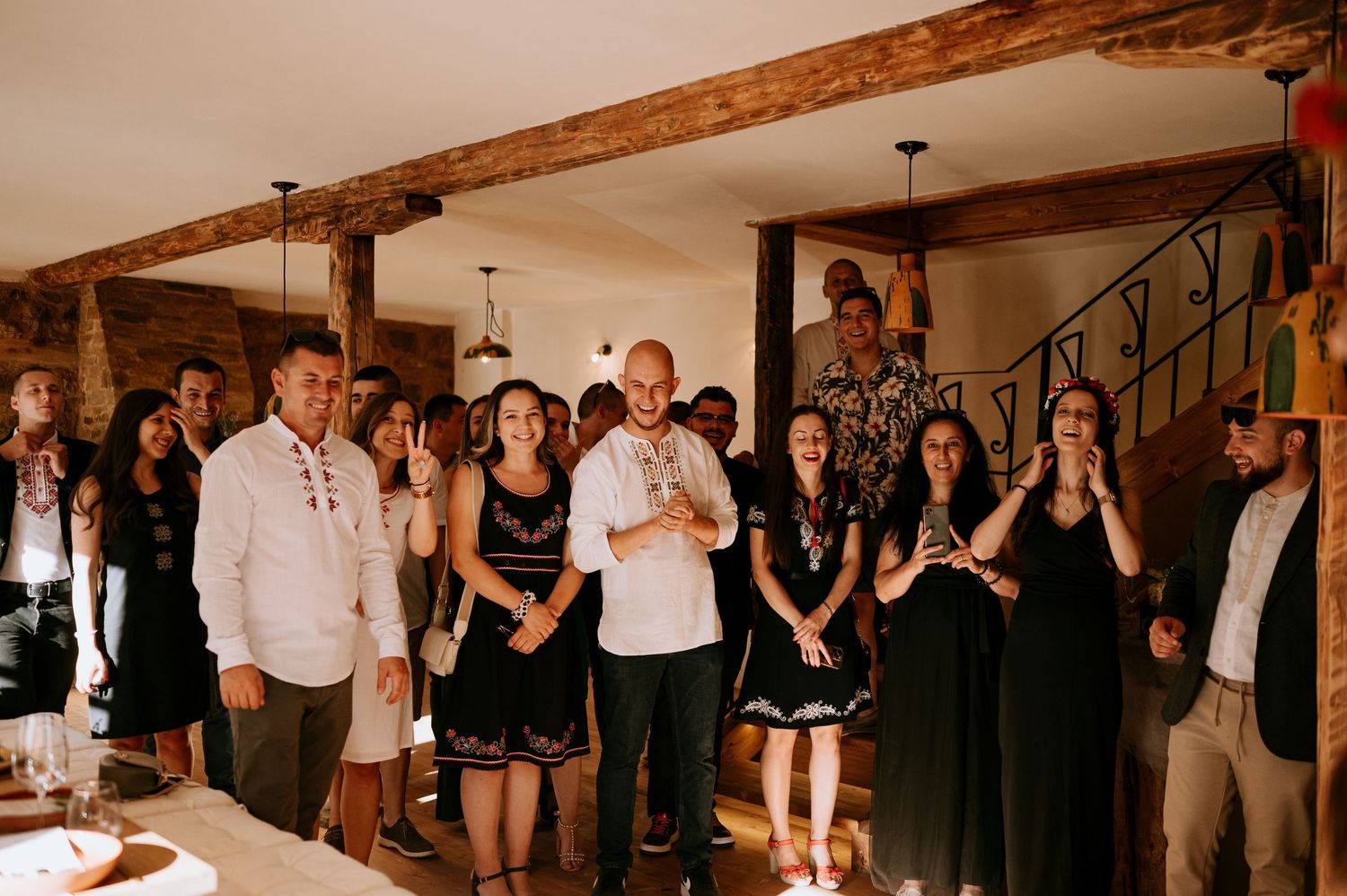 Celebration gathering in a rustic venue with exposed wooden beams and formal dress code.