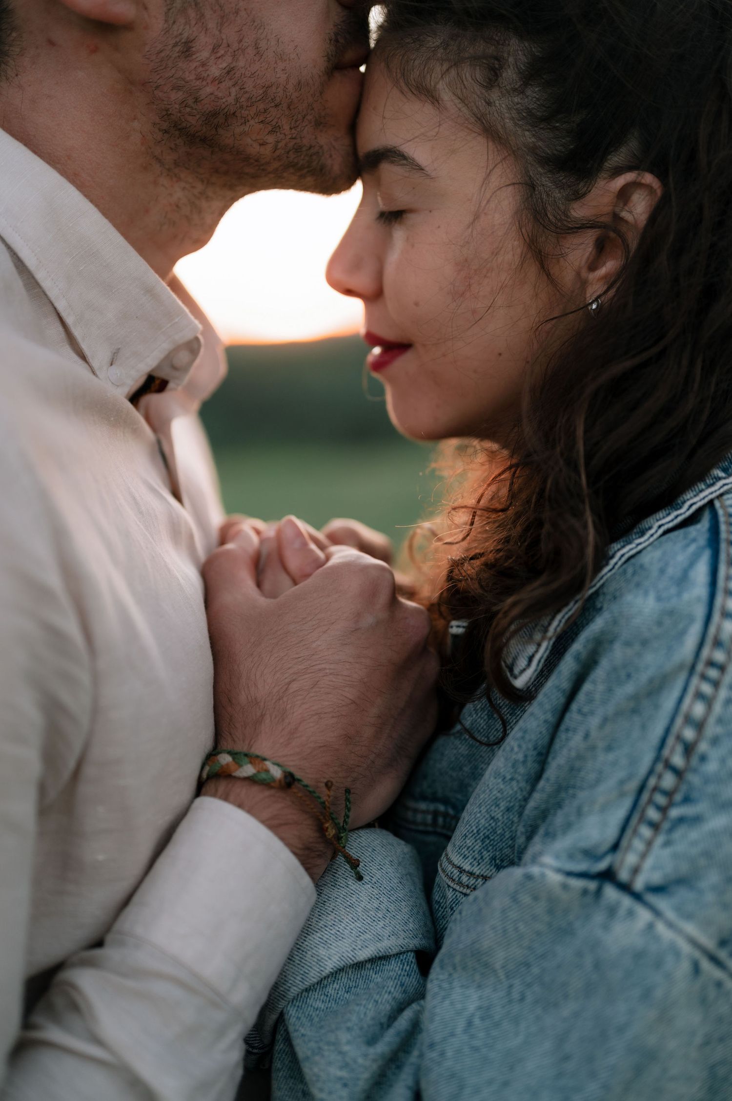 A romantic couple in denim and white sharing an intimate moment against a blurred background.