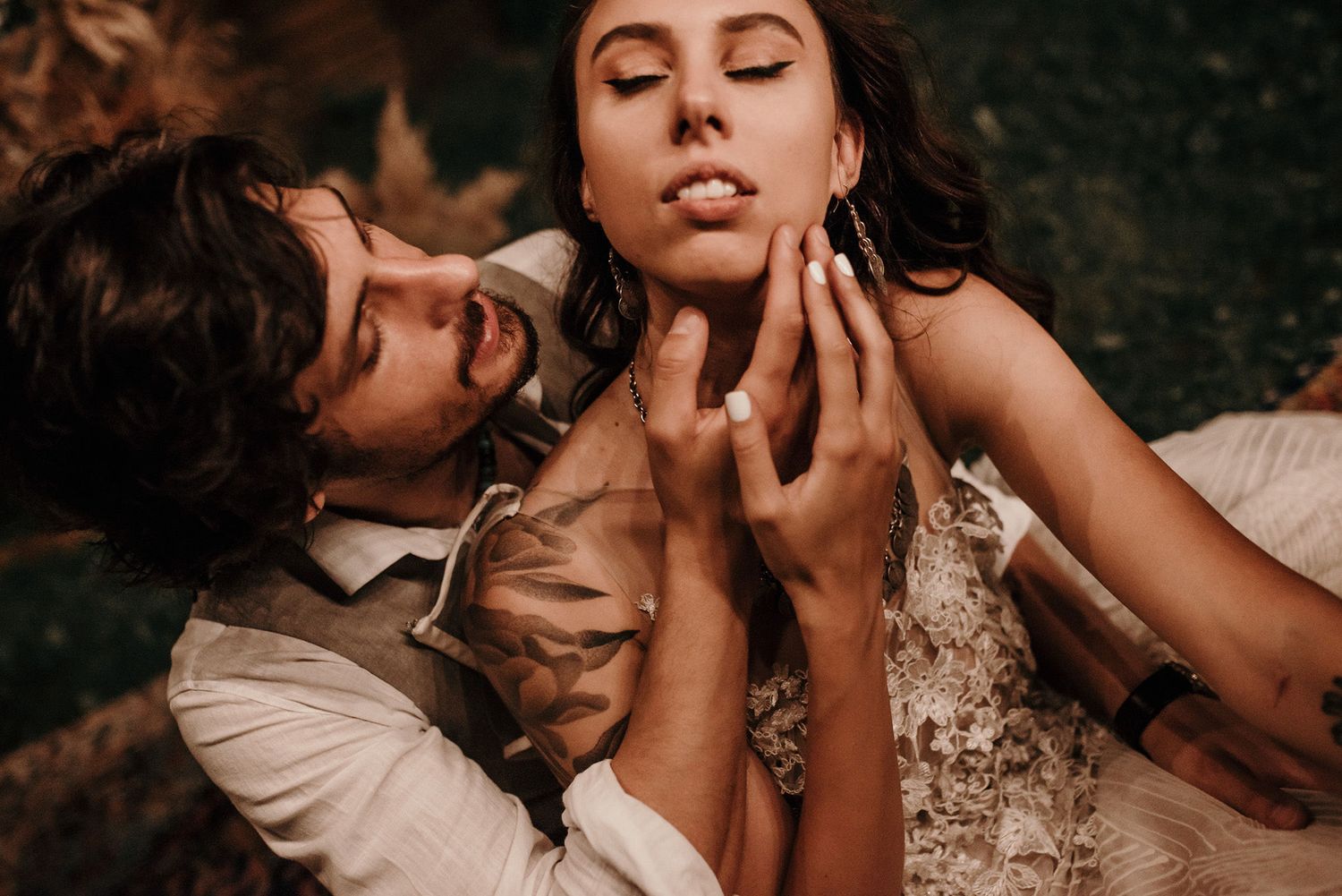 A romantic couple in vintage-inspired wedding attire share an intimate moment outdoors during a photo session.