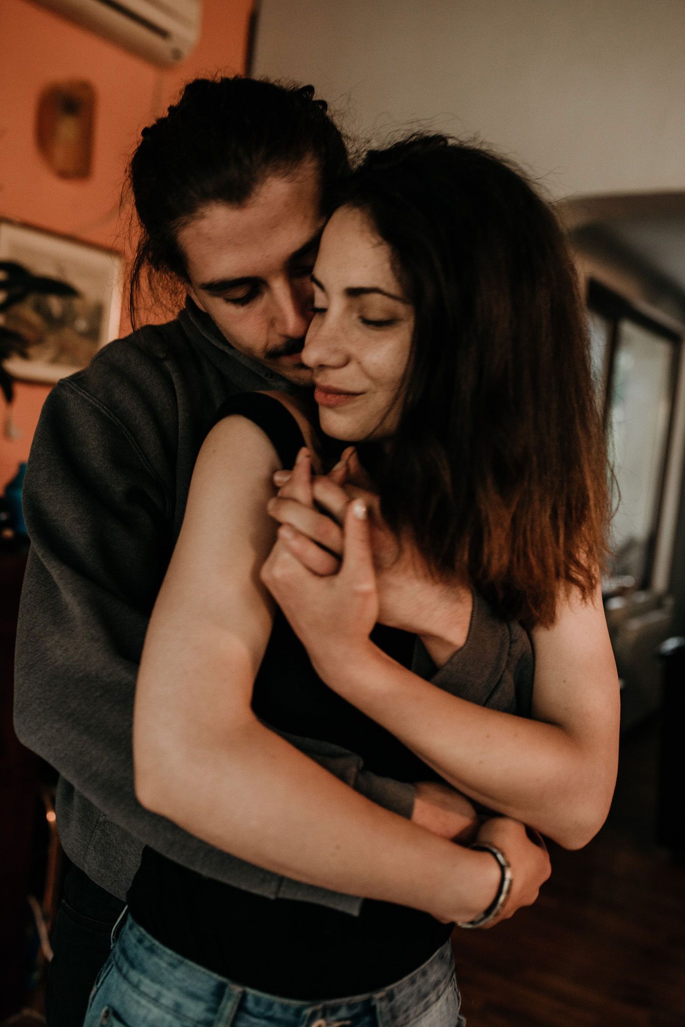 A romantic couple embraces intimately in a dimly lit indoor setting, shown in a series of candid moments.