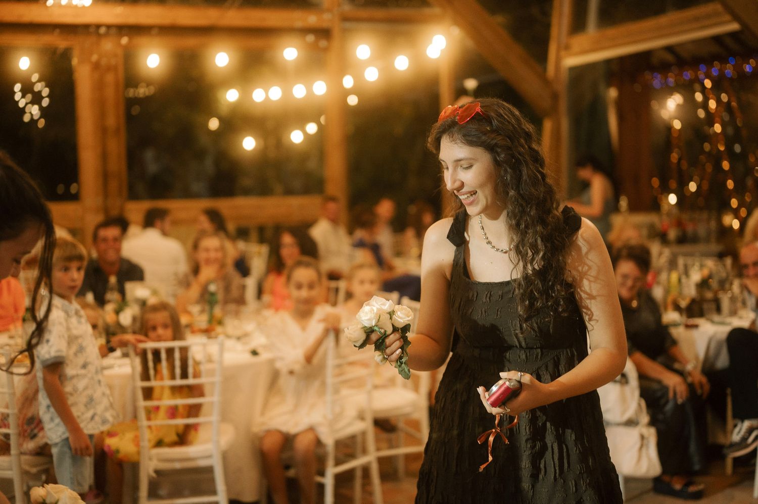 Wedding reception guests enjoy a candlelit evening celebration with warm string lights and rustic decor.