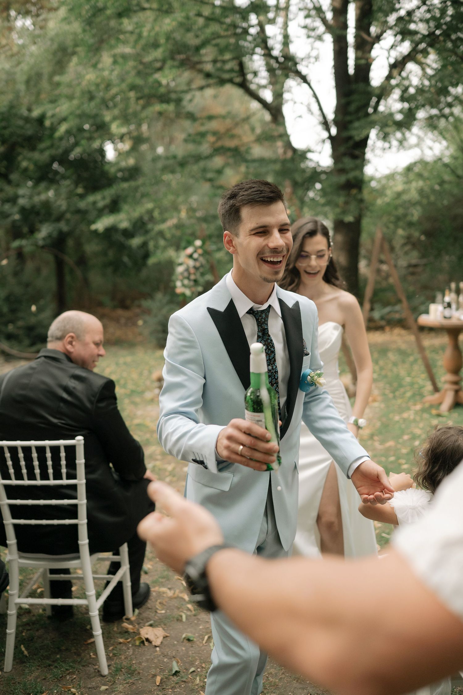 A group of wedding guests in an outdoor garden setting toasting with champagne glasses.