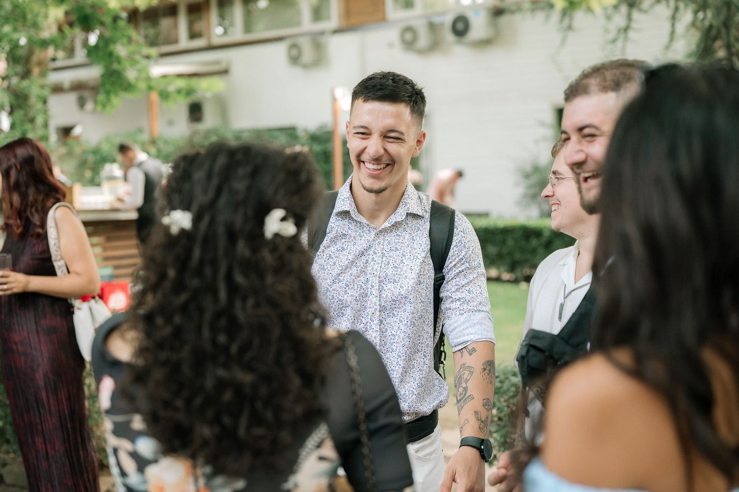 A group of people laughing and enjoying conversation at an outdoor social gathering.
