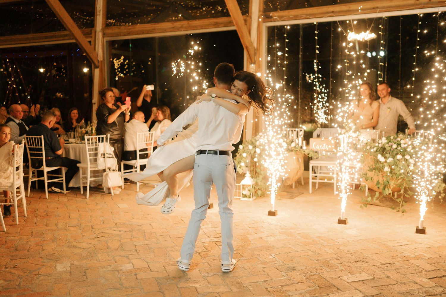 Dancers perform energetic moves on a dance floor illuminated by dramatic sparkler fountains at a celebration event.