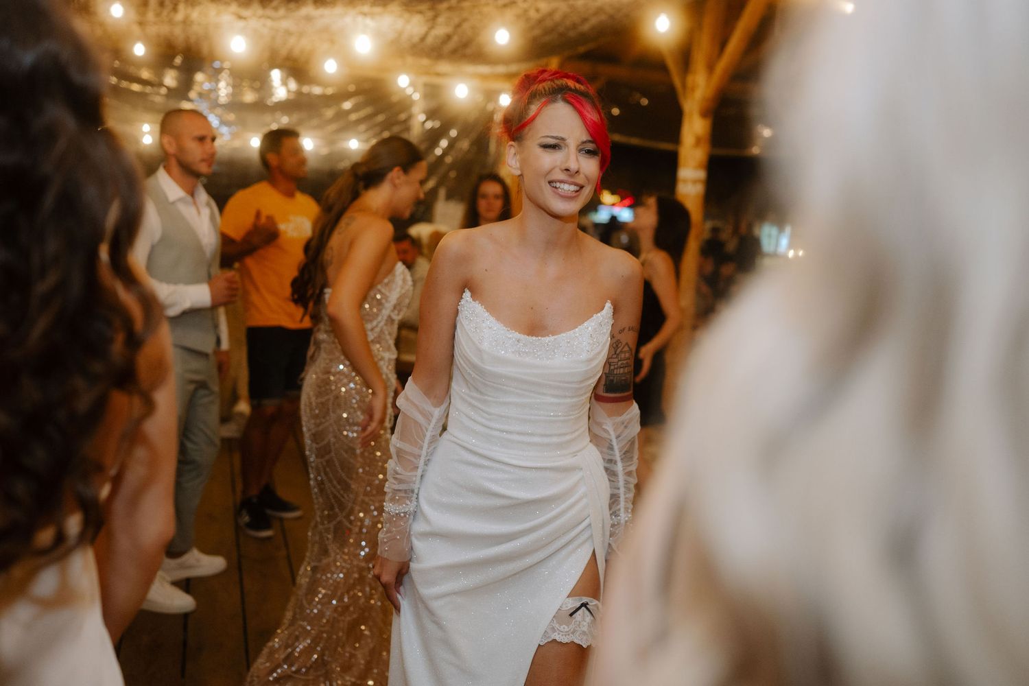 Guests dancing and celebrating at a lively wedding reception under warm glowing lights.