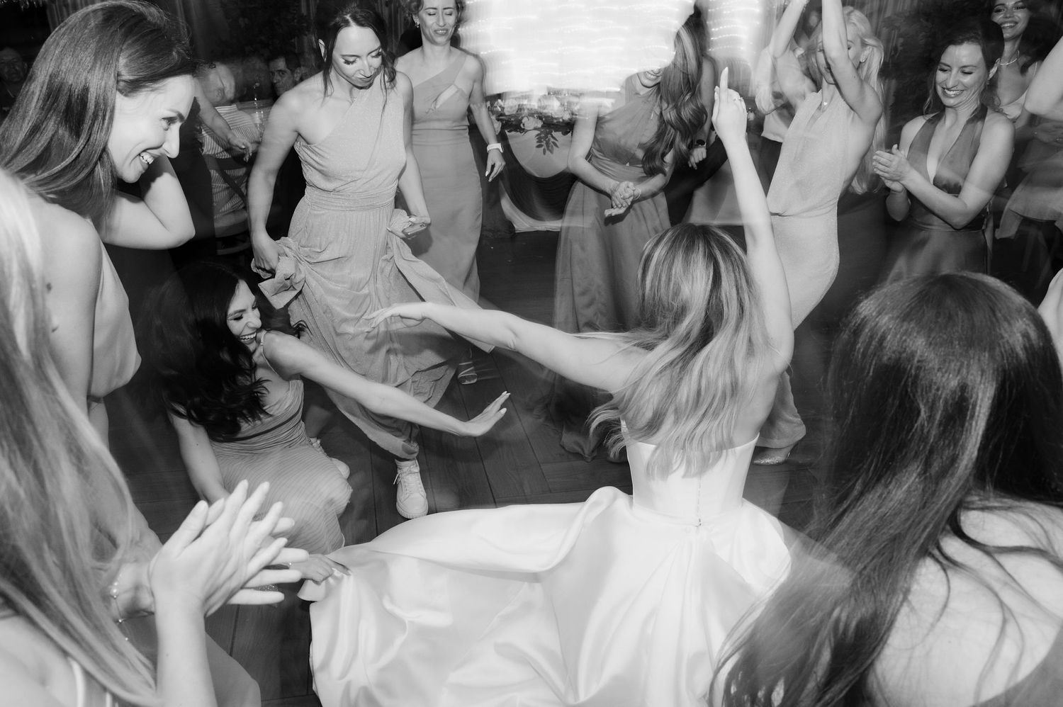 People dancing and celebrating at a wedding reception on a crowded dance floor.