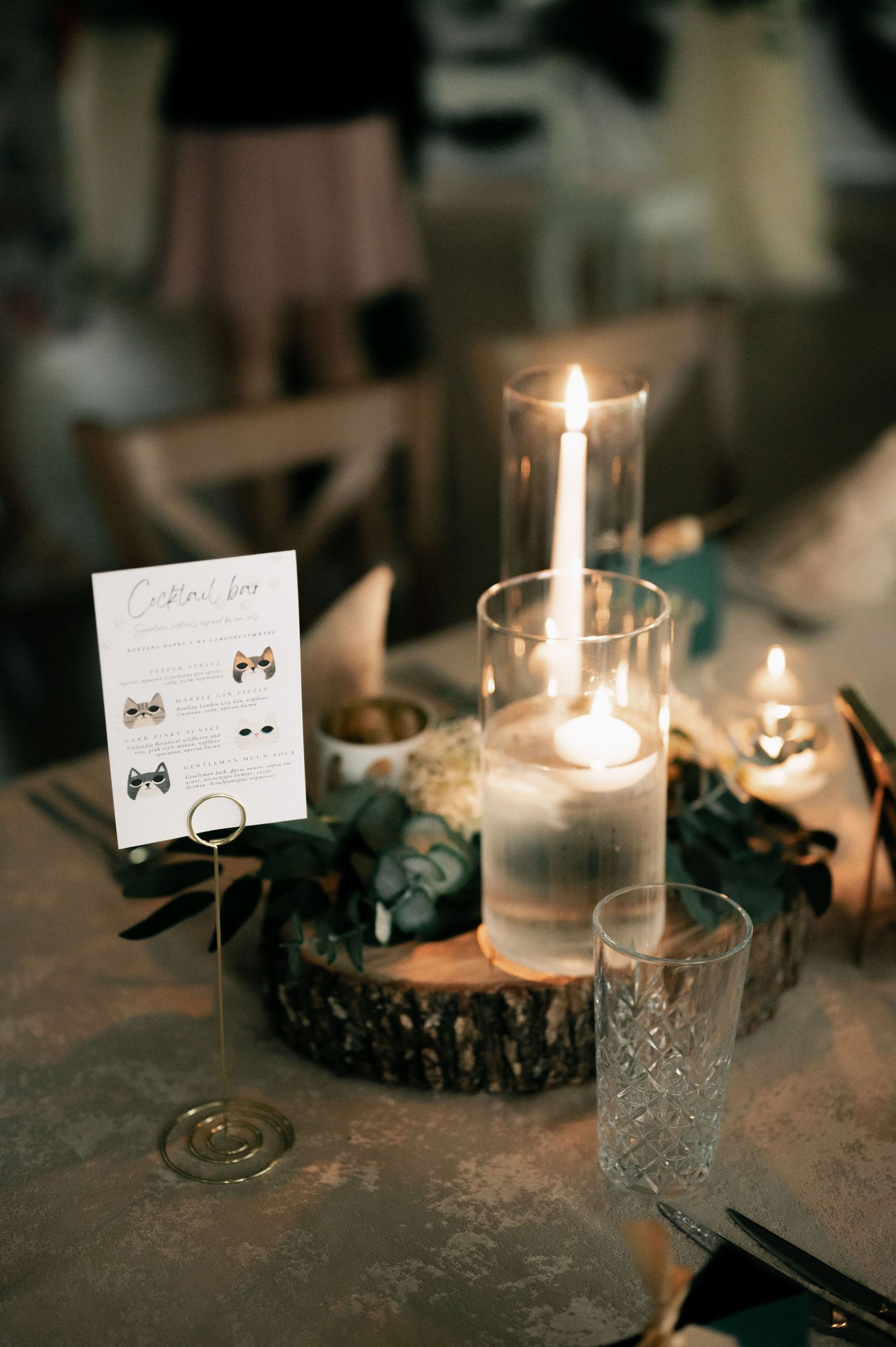 Elegant table setting with glowing candles in glass holders and small place cards creating a romantic ambiance.