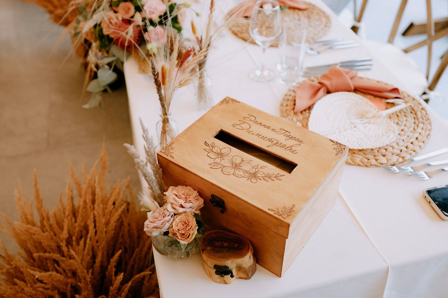 Rustic wedding reception table decorated with pampas grass, blush roses, and vintage-inspired place settings.