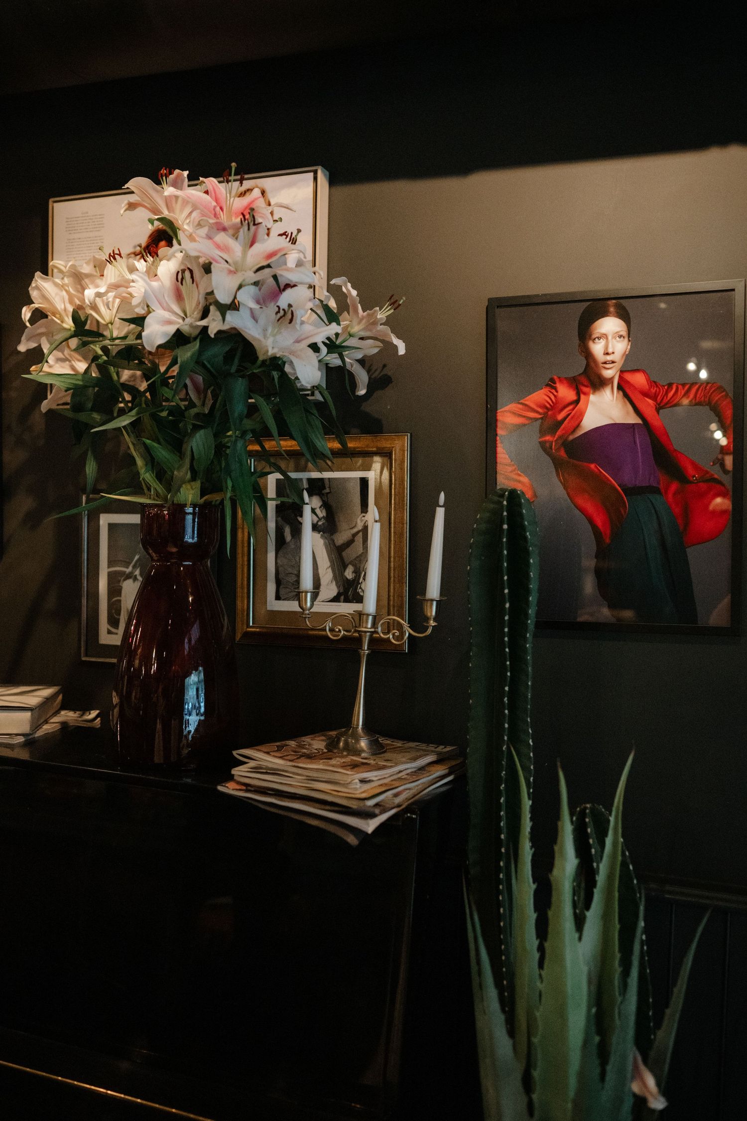 A series of artistic photographs showing a floral arrangement with pink lilies atop tall green succulent plants in a dark setting.