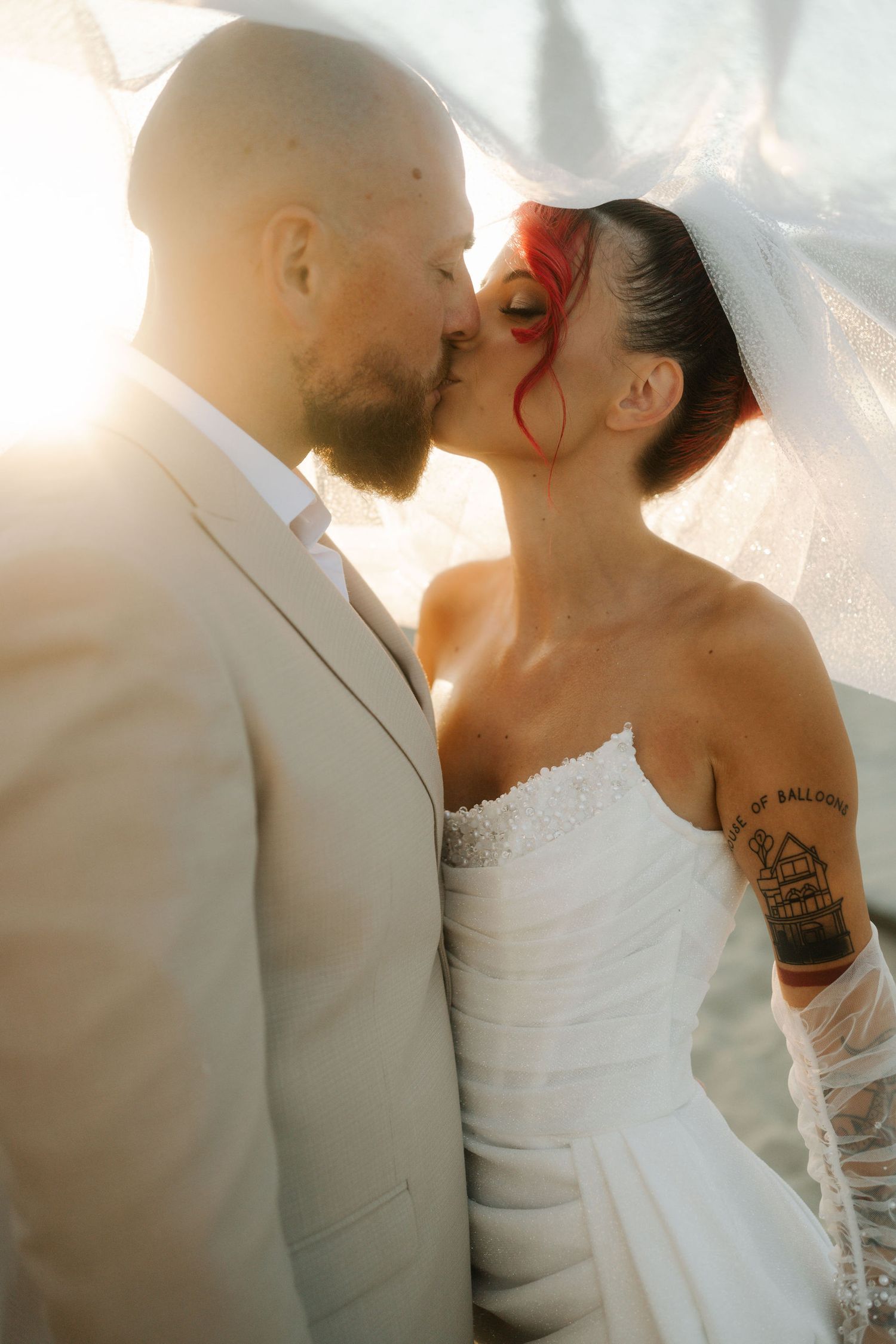 Romantic wedding couple shares an intimate kiss at sunset with soft glowing light creating a dreamy atmosphere.