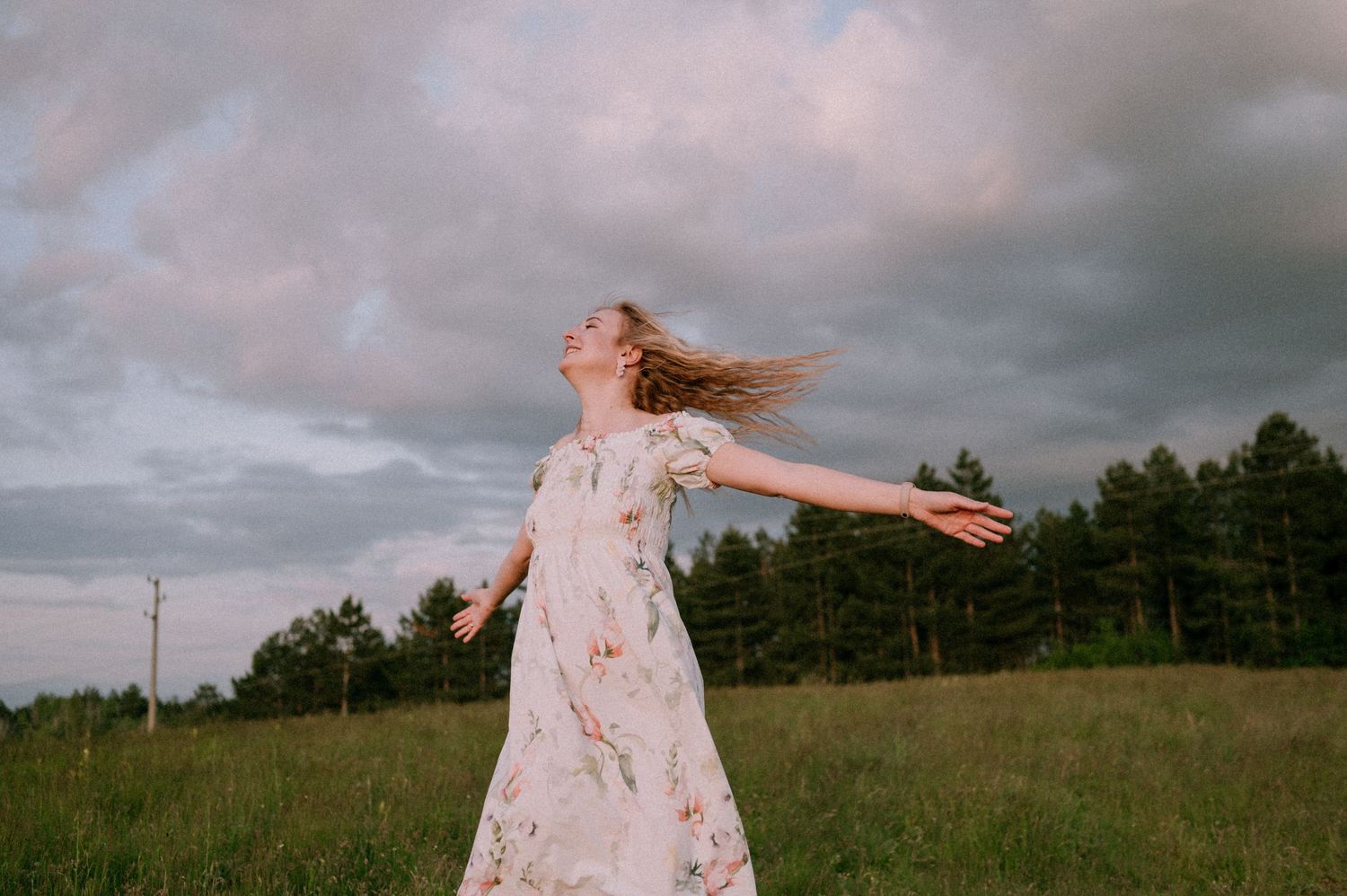 A person twirls with arms outstretched in a summer meadow.