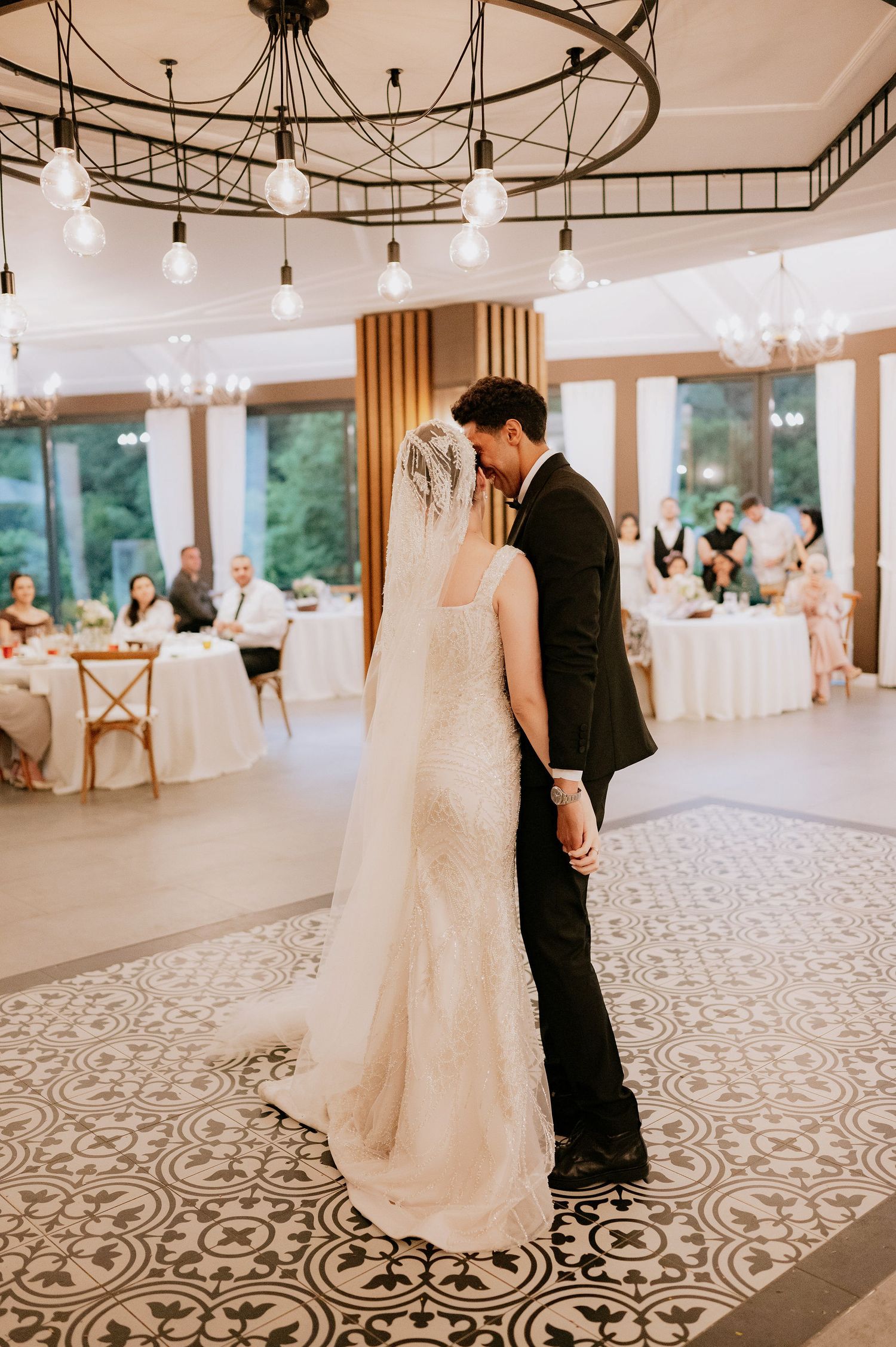 Elegant wedding reception venue with patterned floor and pendant lighting.
