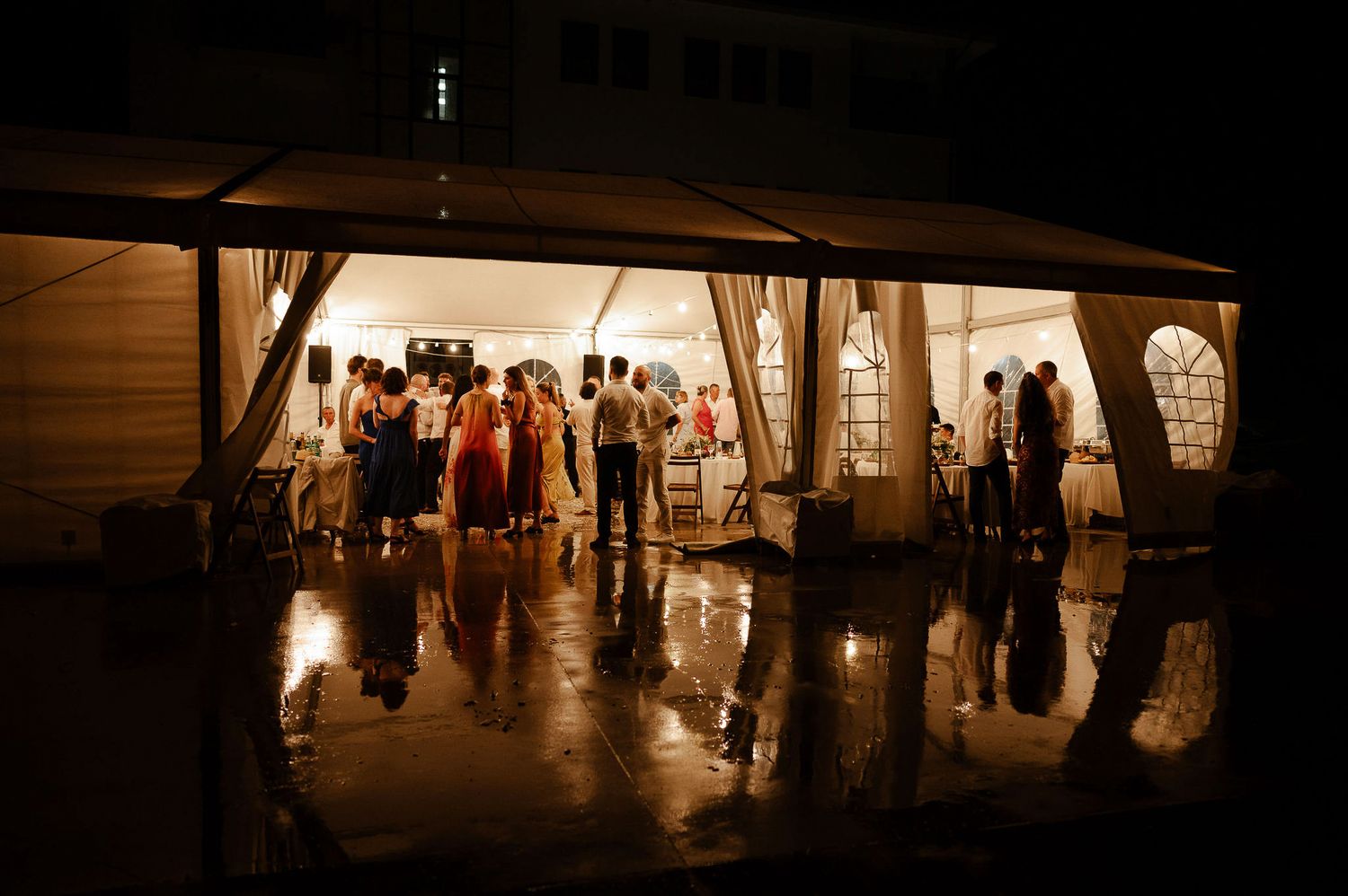Silhouettes of wedding guests dancing in a dimly lit reception venue.
