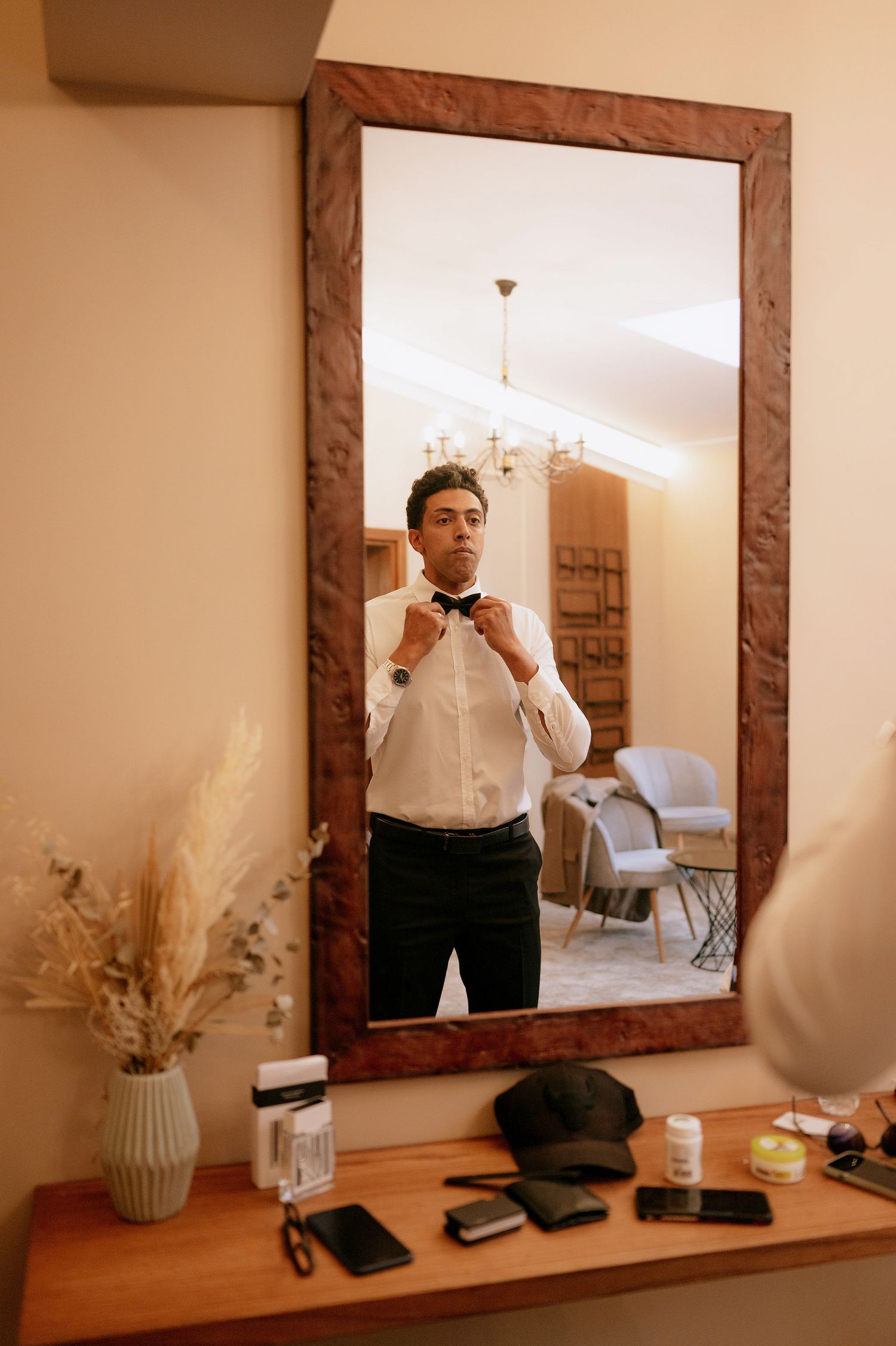 Mirror reflection showing formal wear preparations with grooming items on wooden shelf.
