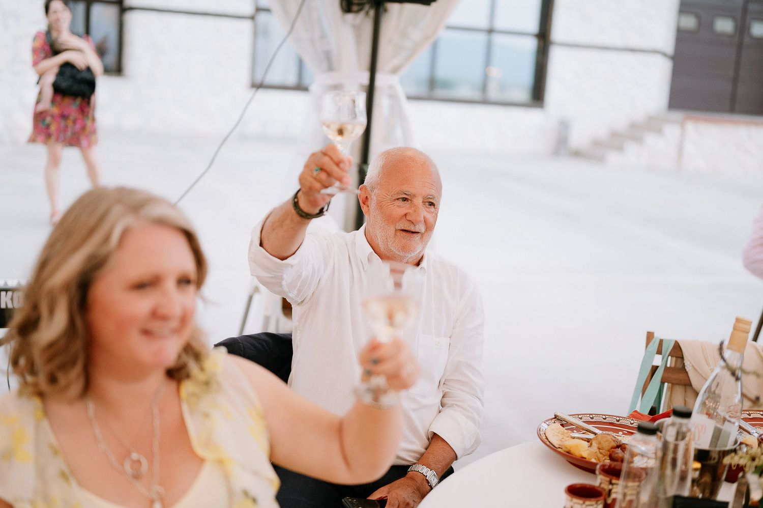 Wedding guests raise their glasses in a toast during the reception celebration.