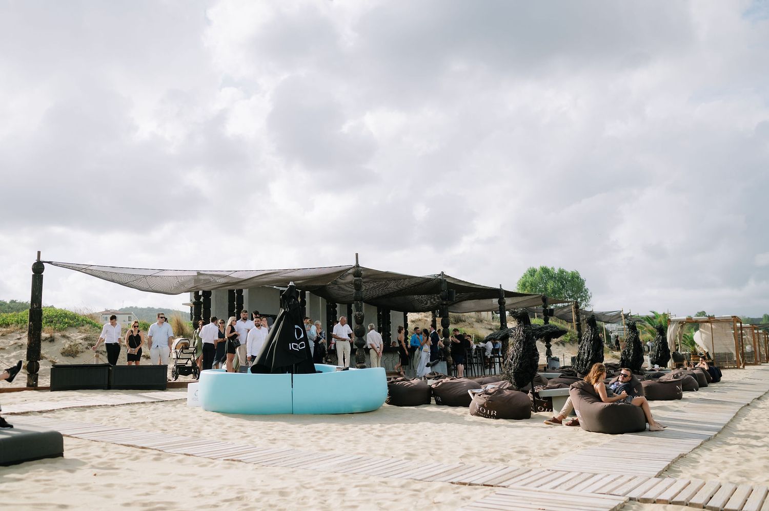 Outdoor wedding reception setup with tents and seating on the beach.
