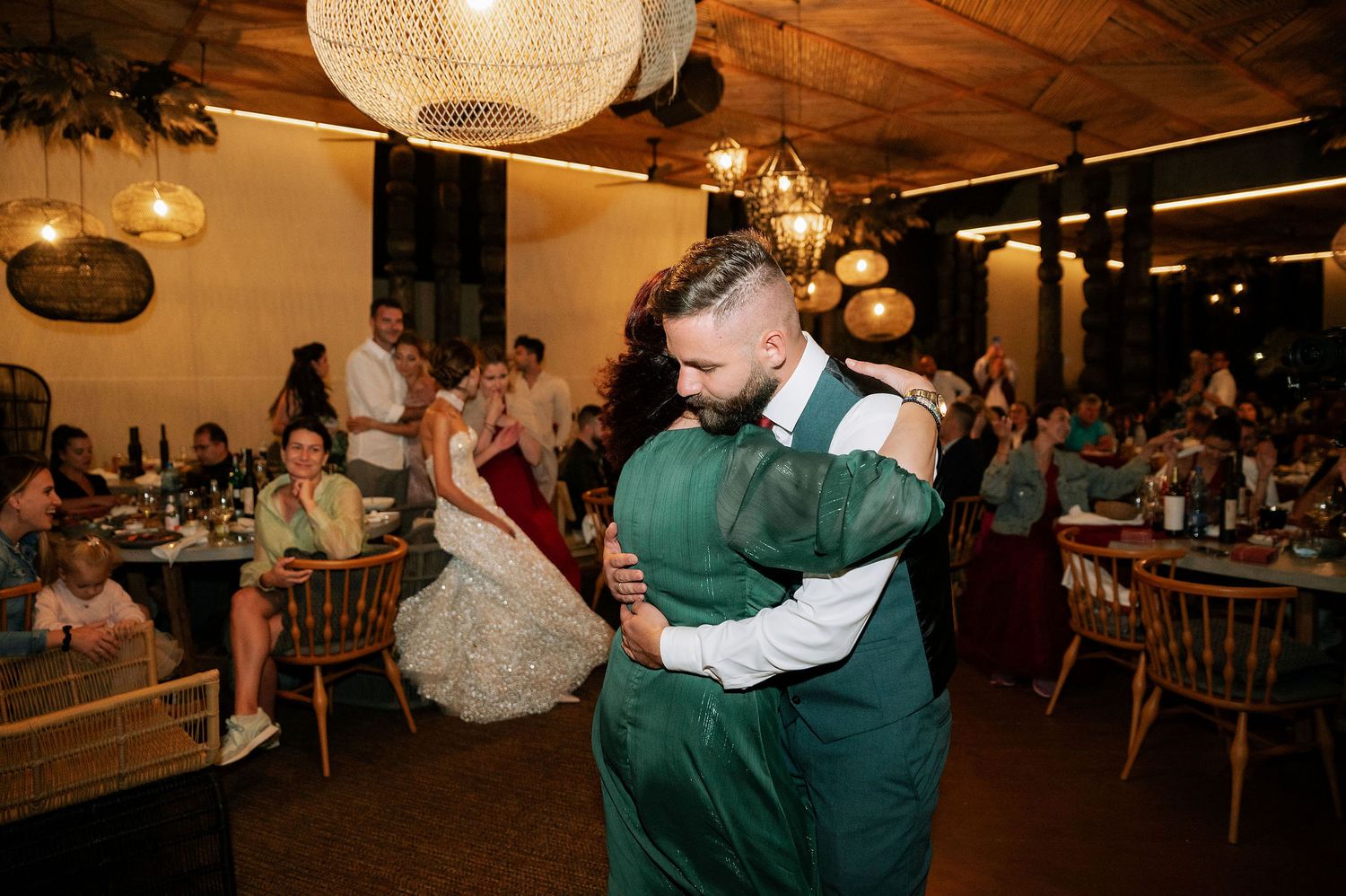 Wedding reception dance floor filled with guests under rustic pendant lighting.