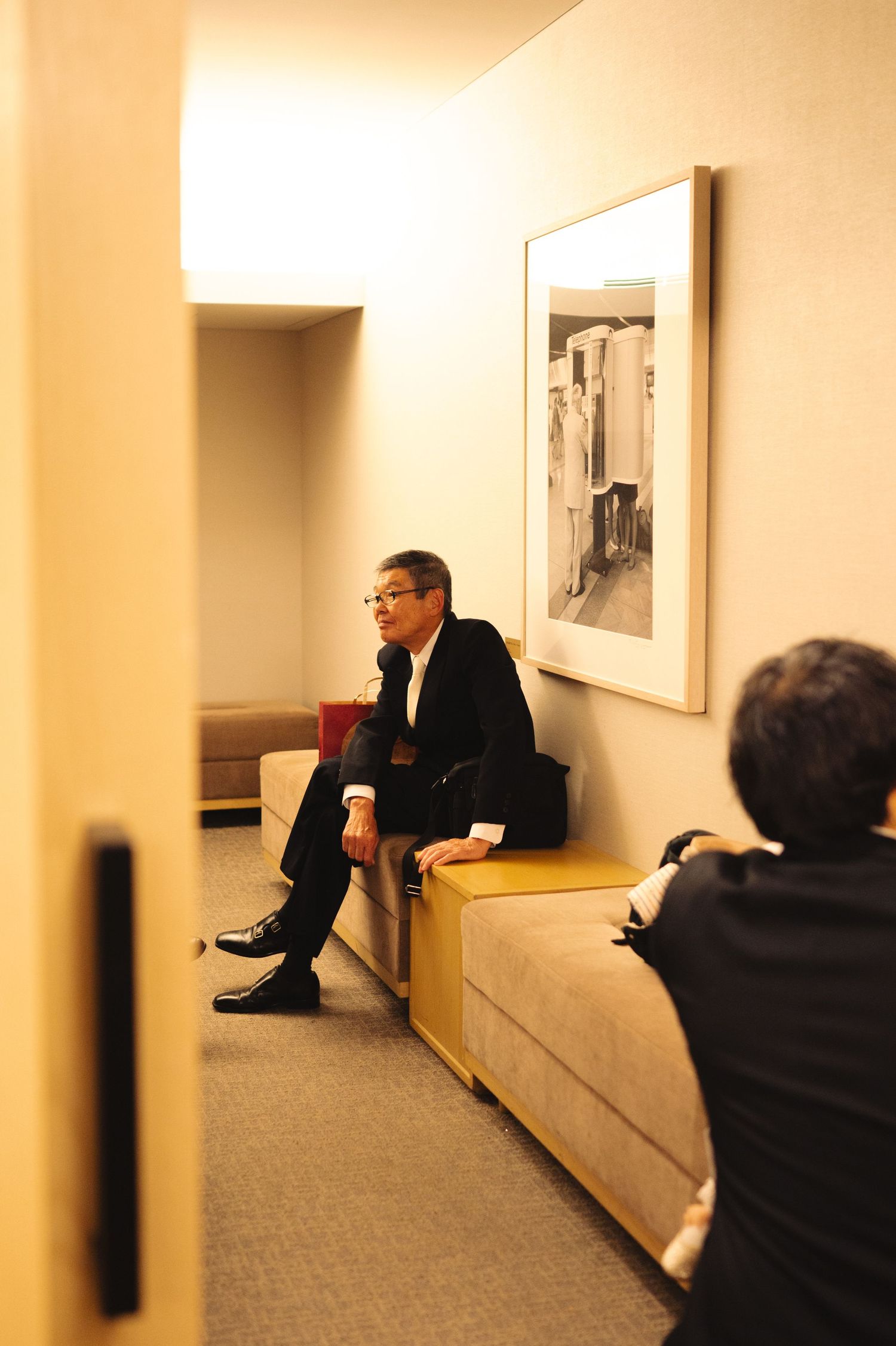 Guests in formal wear gathered in a beige-walled hallway during an event.