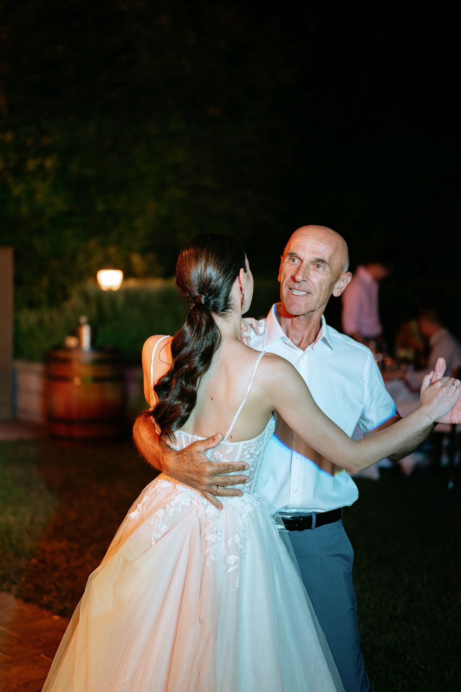 A couple dances together during their wedding reception on an outdoor patio.