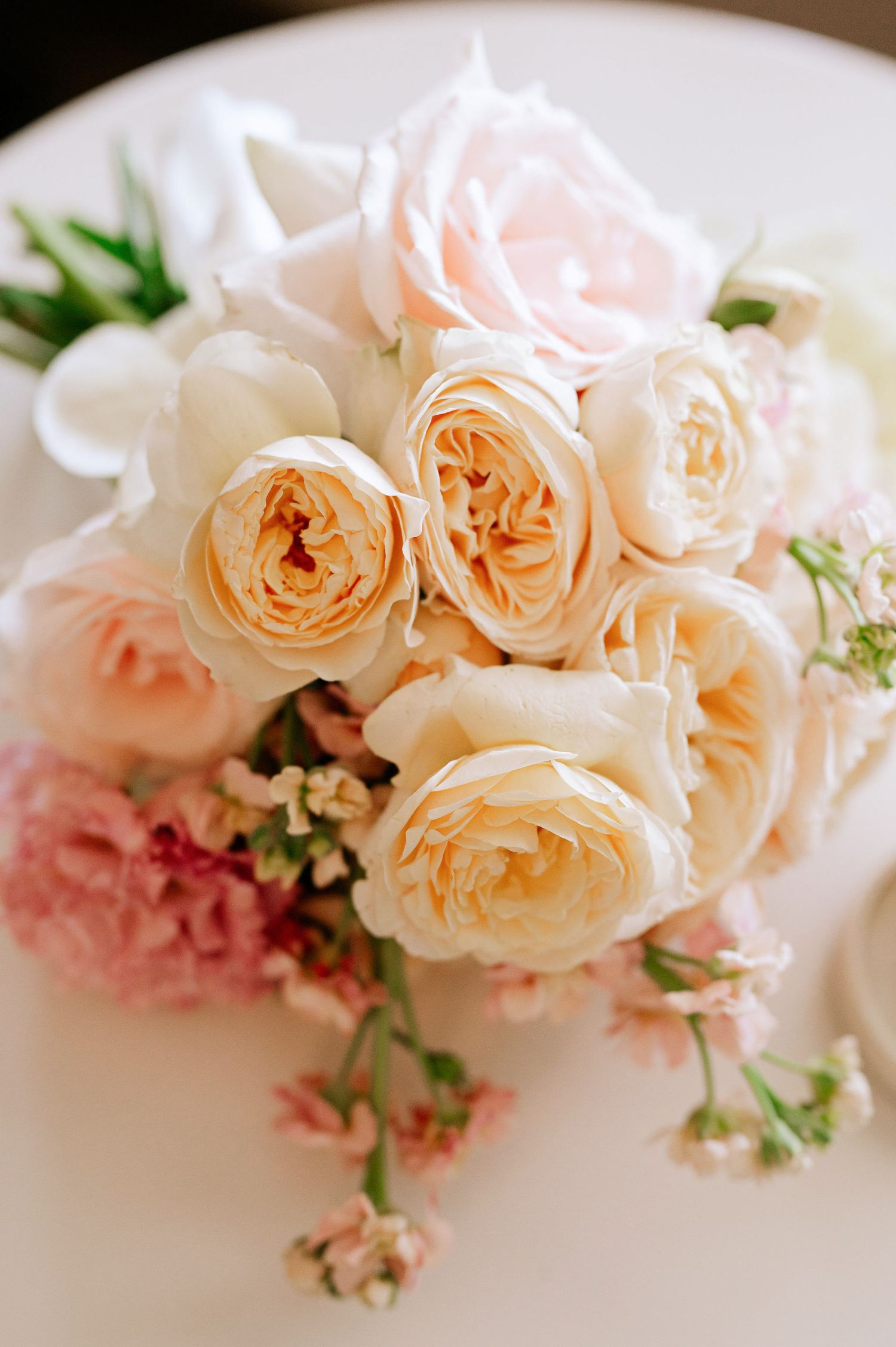 Close-up of delicate peach garden roses and pink flowers in a romantic wedding arrangement.