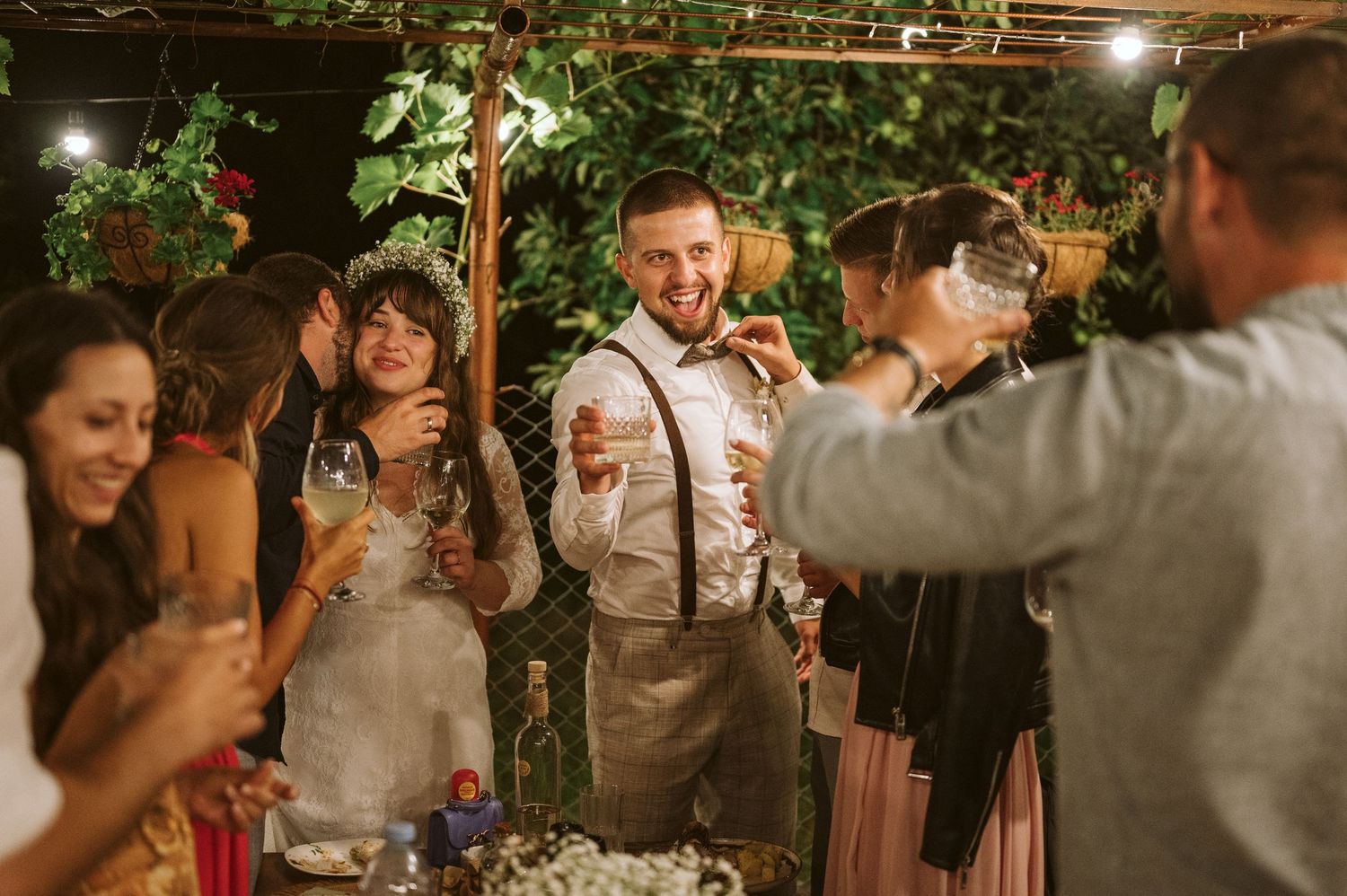 Guests dancing and celebrating at a romantic outdoor wedding reception under string lights and greenery.