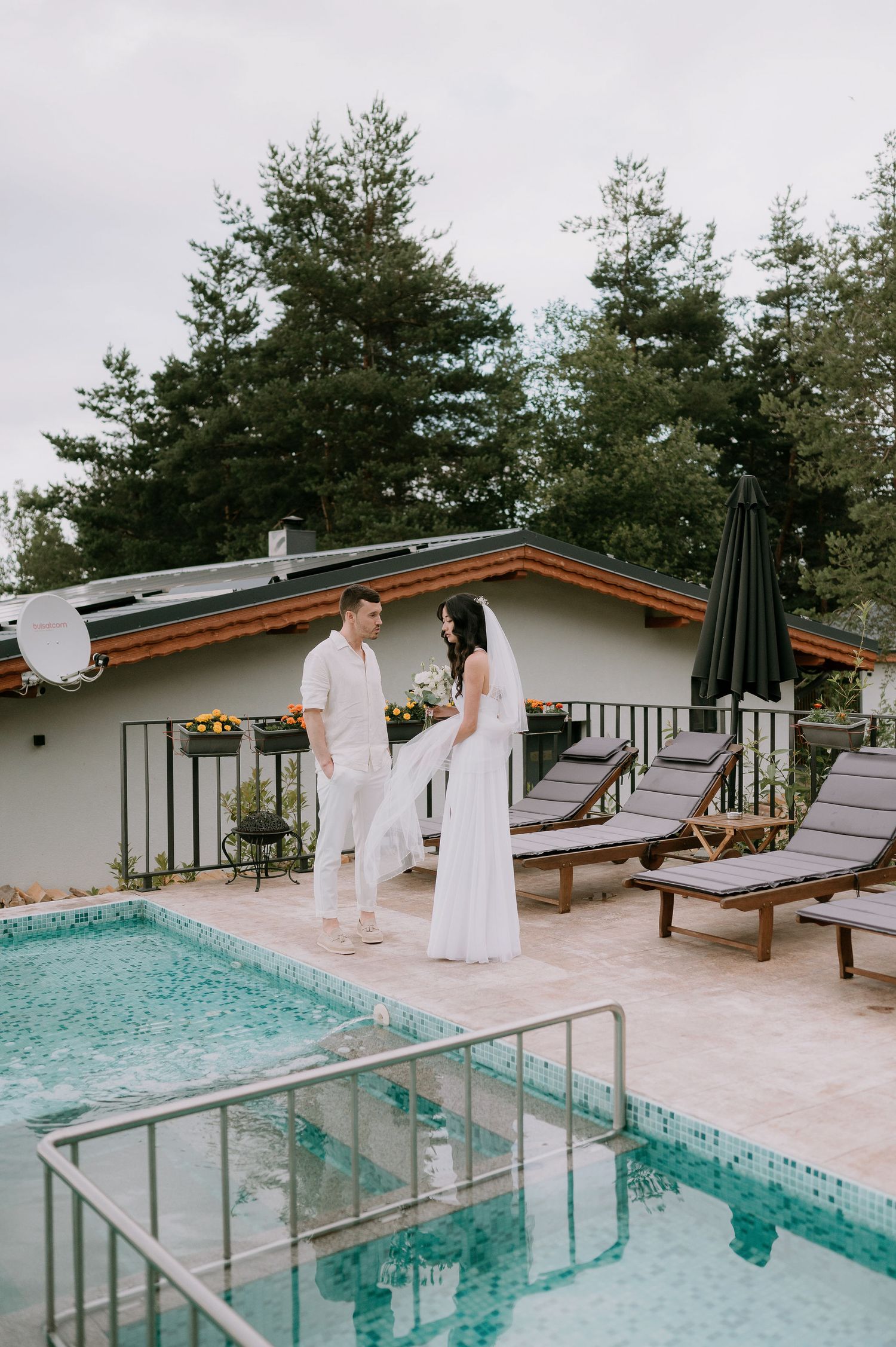 Elegant outdoor pool area with wooden lounge chairs and pine forest backdrop.