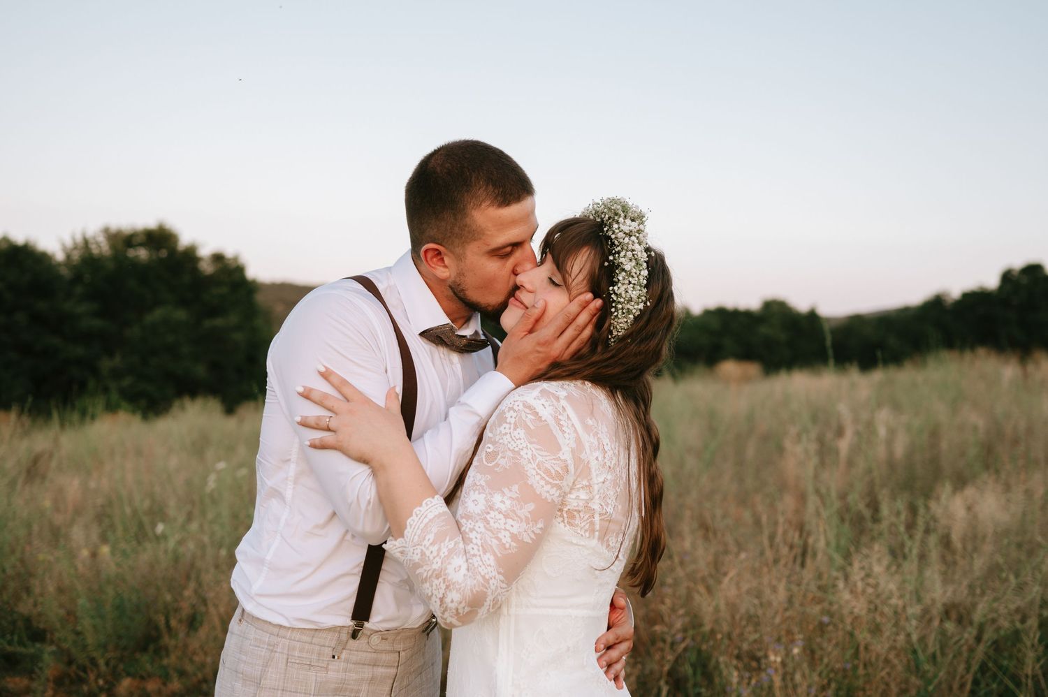 Intimate moment between newlyweds in a golden field during sunset.