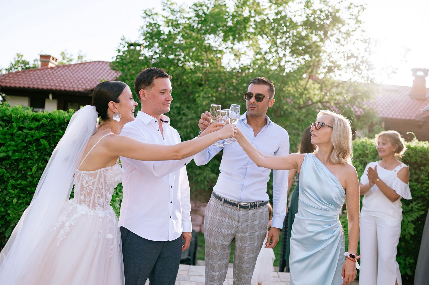 Wedding celebration with guests toasting and enjoying drinks on stone patio.