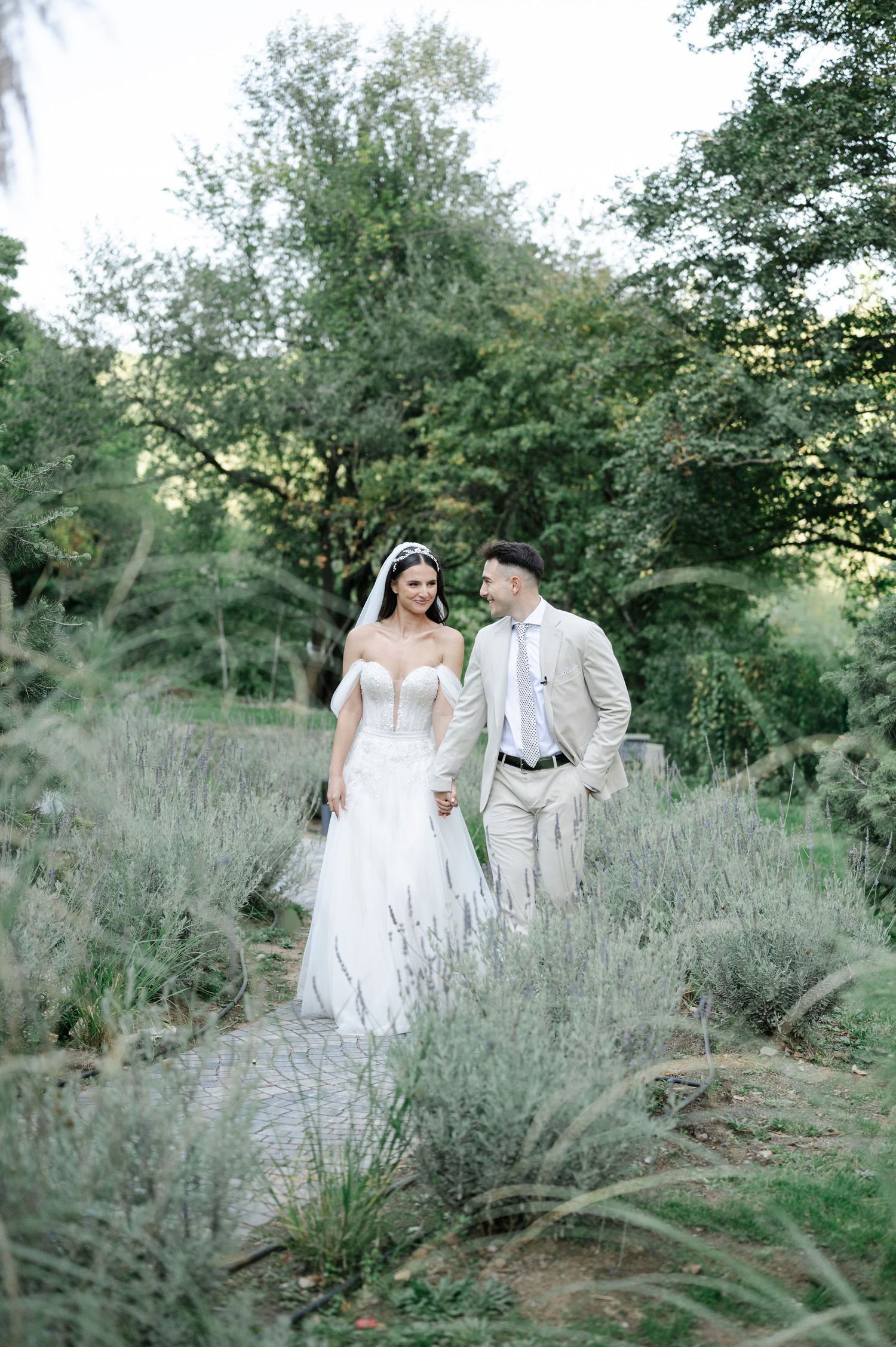 Newlyweds pose elegantly among wild grasses and trees during outdoor photo session.