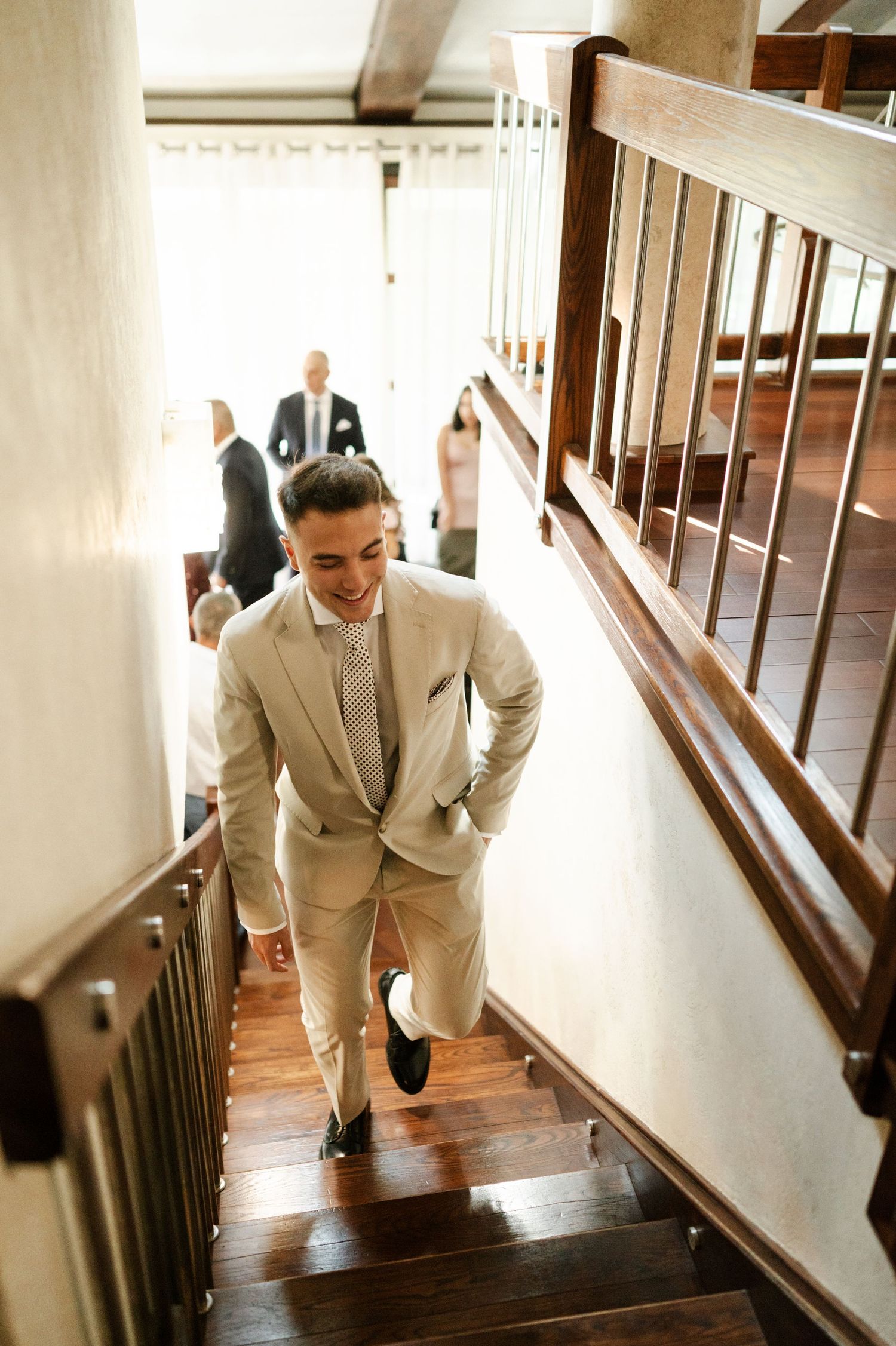 A person in a light-colored suit climbs stairs during a wedding celebration.