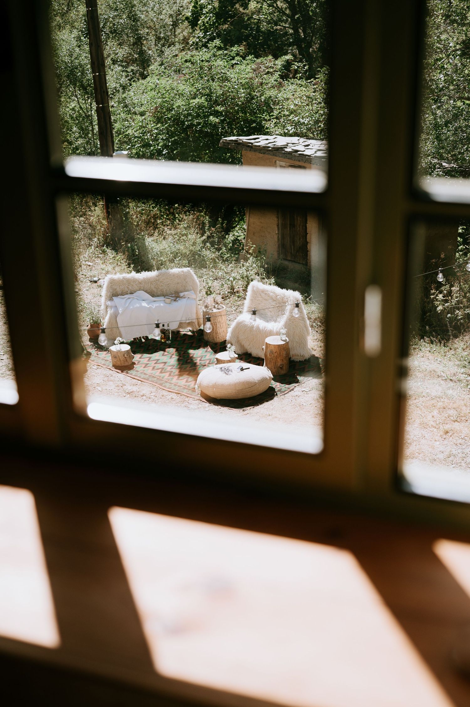 View through window showing outdoor seating area with white furniture.