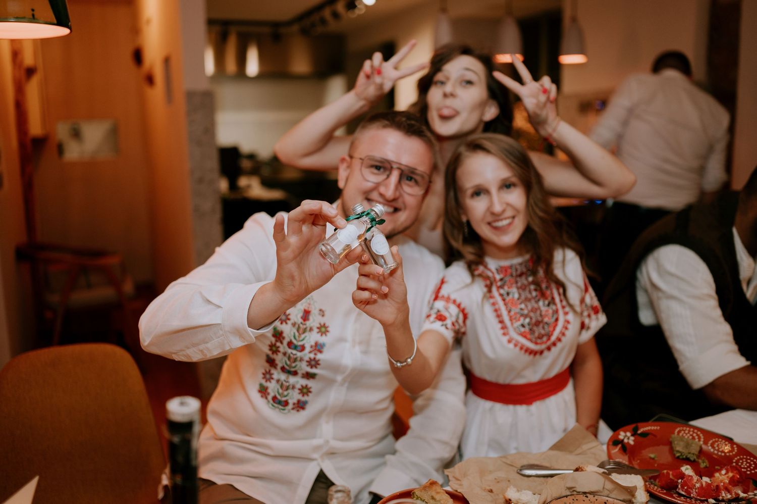 Joyful dinner party scene with guests laughing and celebrating at tables.