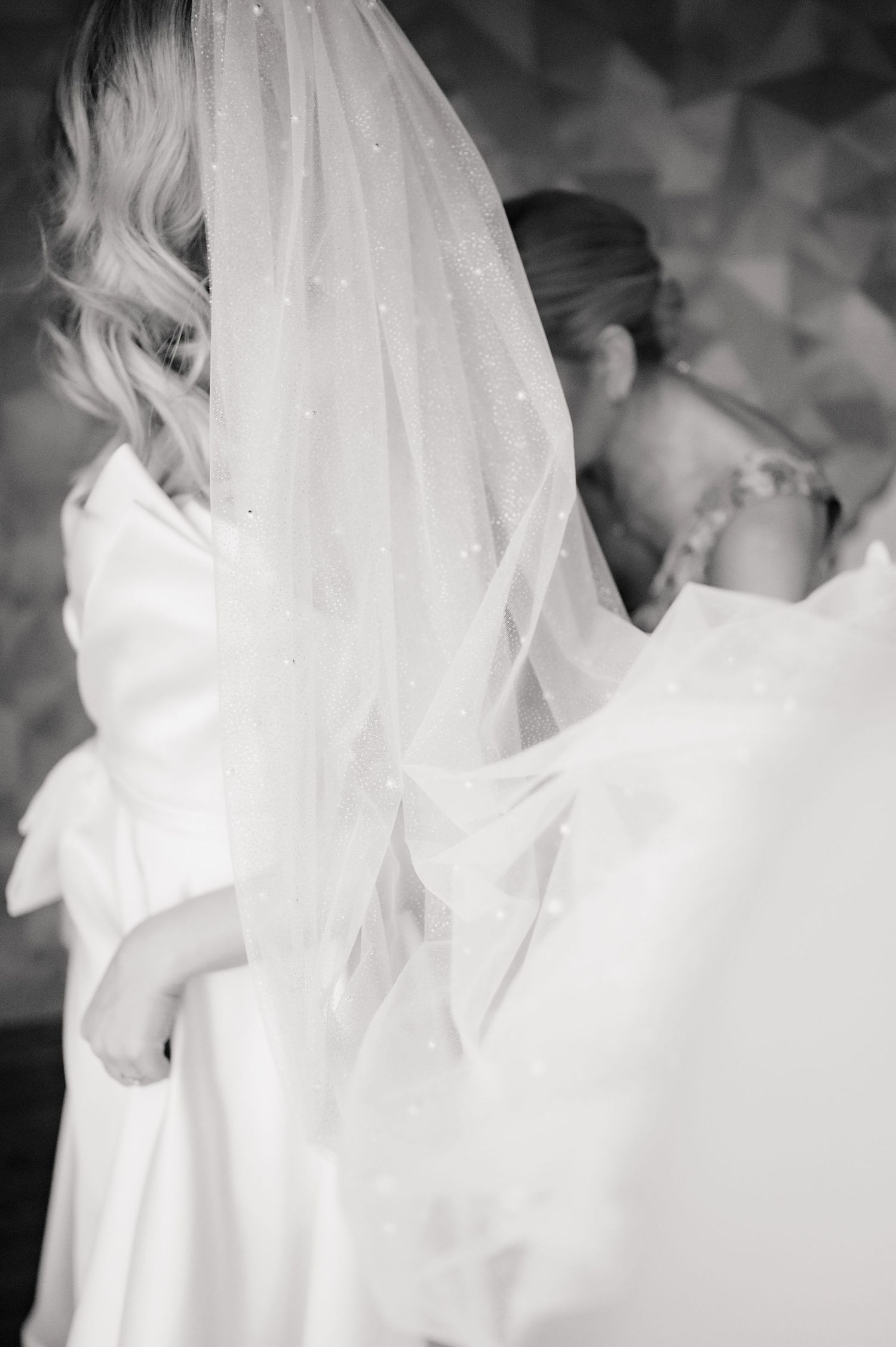 A dreamy black and white photograph showing a delicate wedding veil flowing in soft focus.