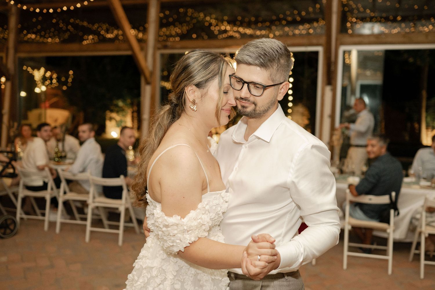 Wedding reception dance floor with string lights overhead creating a romantic outdoor evening atmosphere.