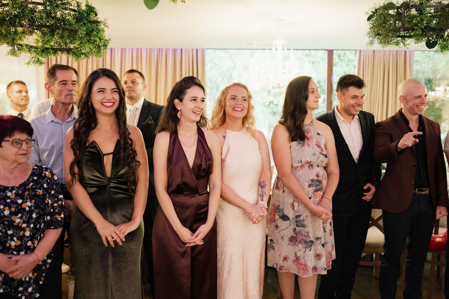 Wedding guests gather in a line during a reception celebration, smiling and enjoying the festivities.