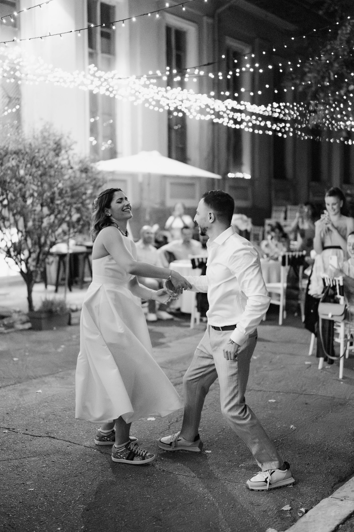 A sequence of black and white photos showing a couple dancing together under twinkling string lights at night.