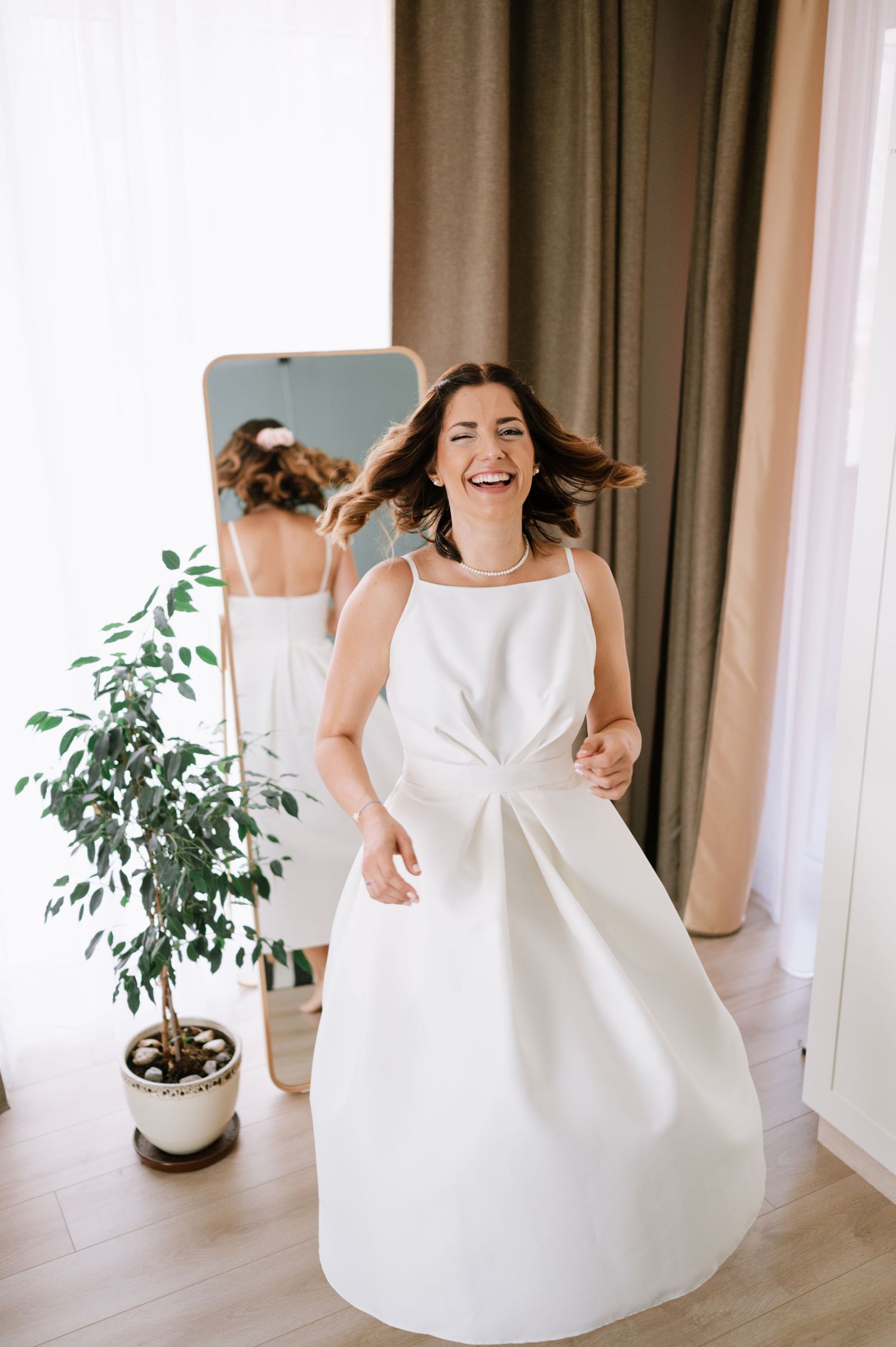 A joyful moment captured in a white wedding dress with a modern twist, featuring a structured bow detail and flowing skirt.