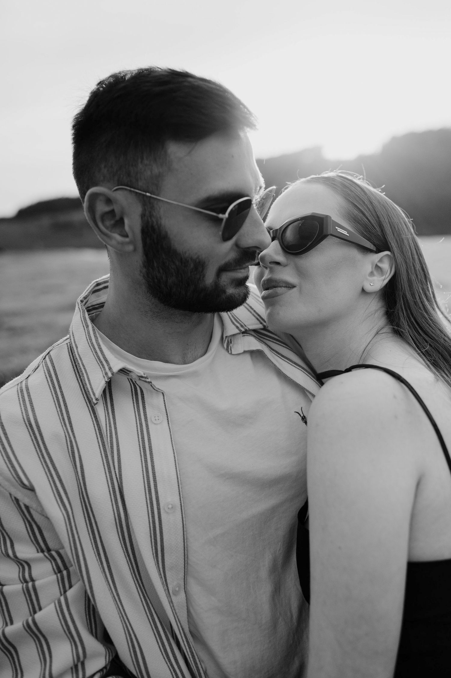 A romantic black and white photo series showing a couple sharing tender kisses at sunset.