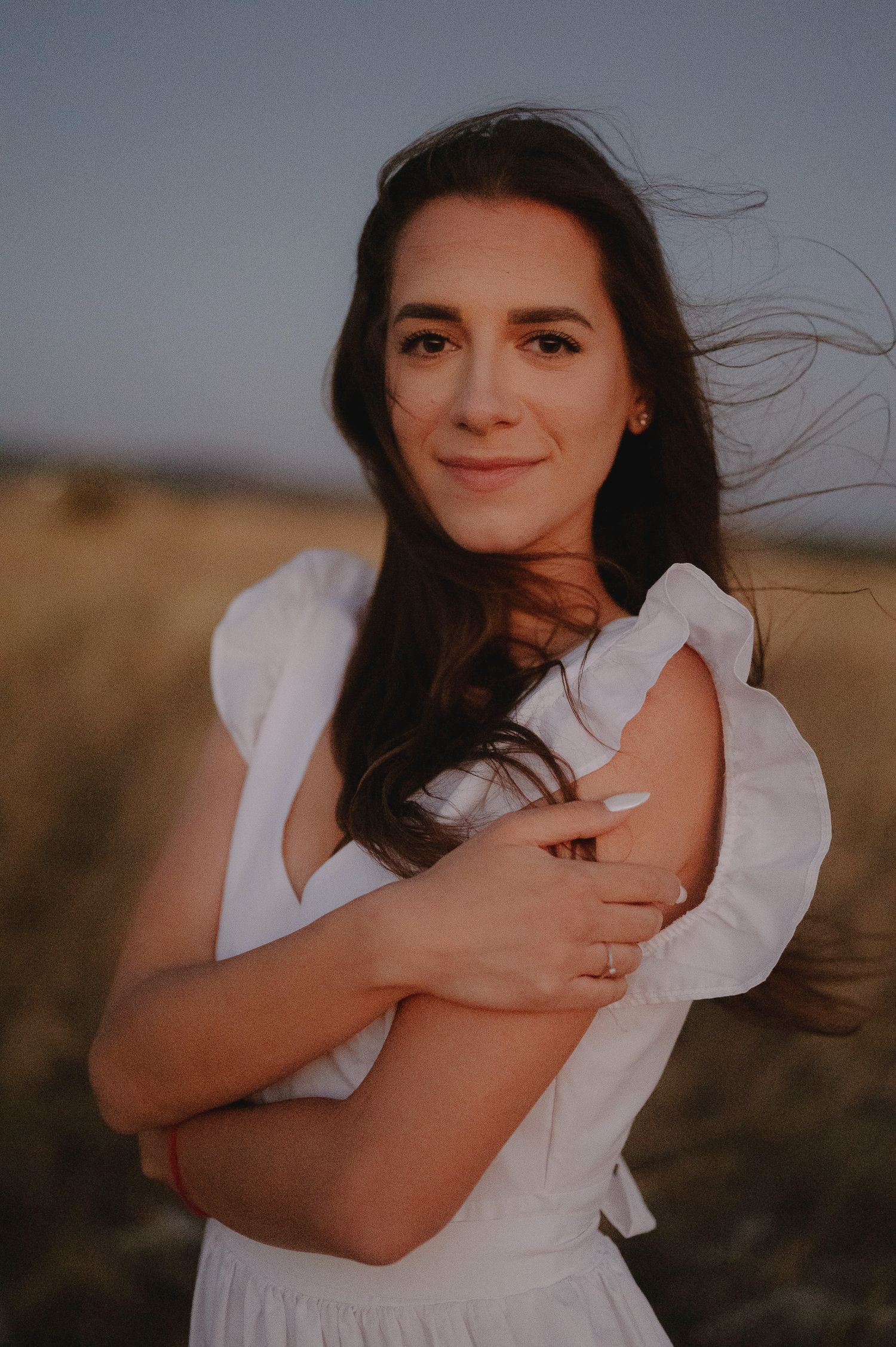 A woman in a white dress poses outdoors in a series of candid shots at sunset.