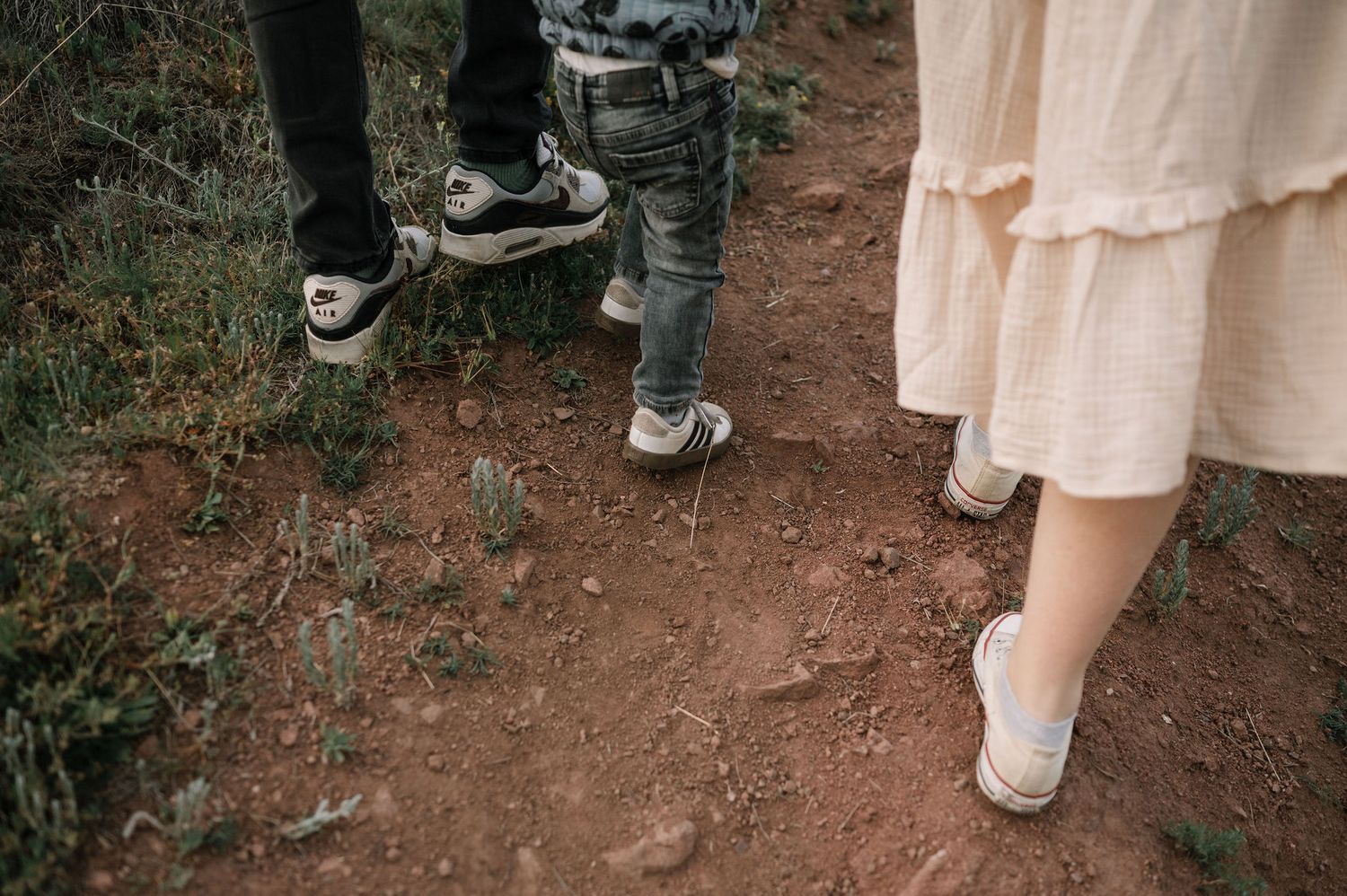 A sequence of photos showing white sneakers walking on a dirt path with a cream colored dress visible.