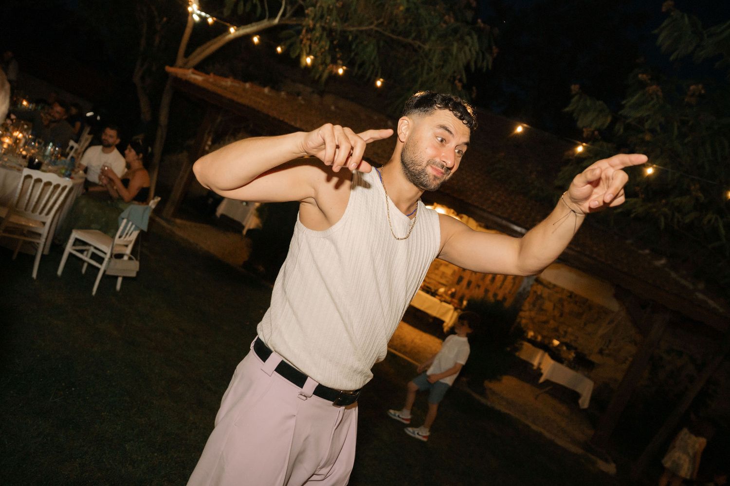People dancing together at an outdoor nighttime event with festive lighting and a lively atmosphere.