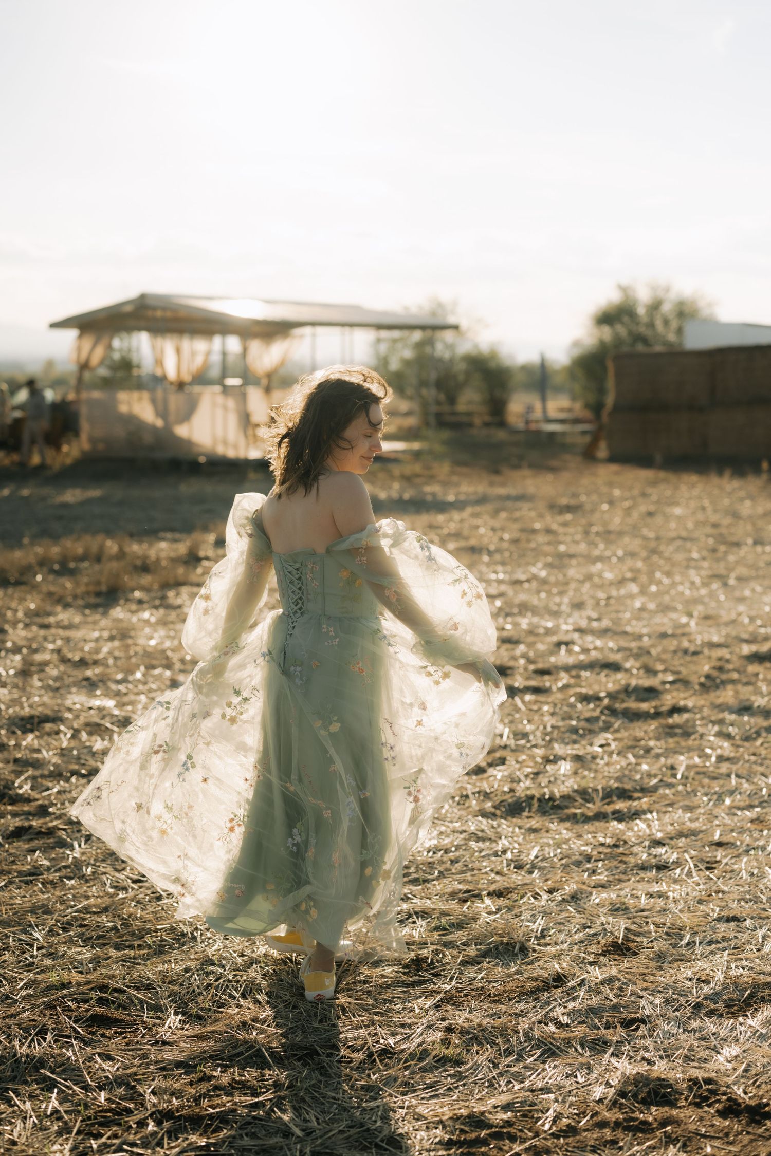 A dreamy scene of a figure in a white flowing dress twirling through a sunlit field at golden hour.