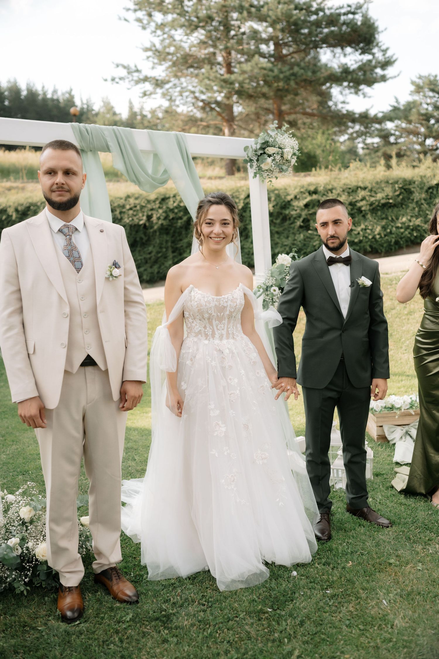 Wedding party members showing off their shoes while standing on grass at an outdoor celebration.